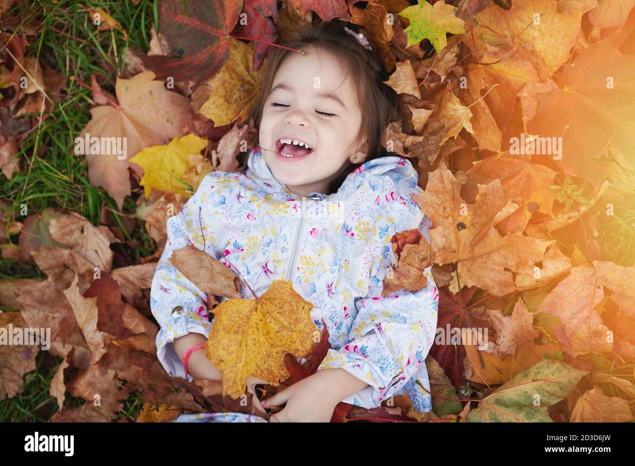 Happy Smile Kind in gelbem Blatt Stapel über Draufsicht Stockfoto