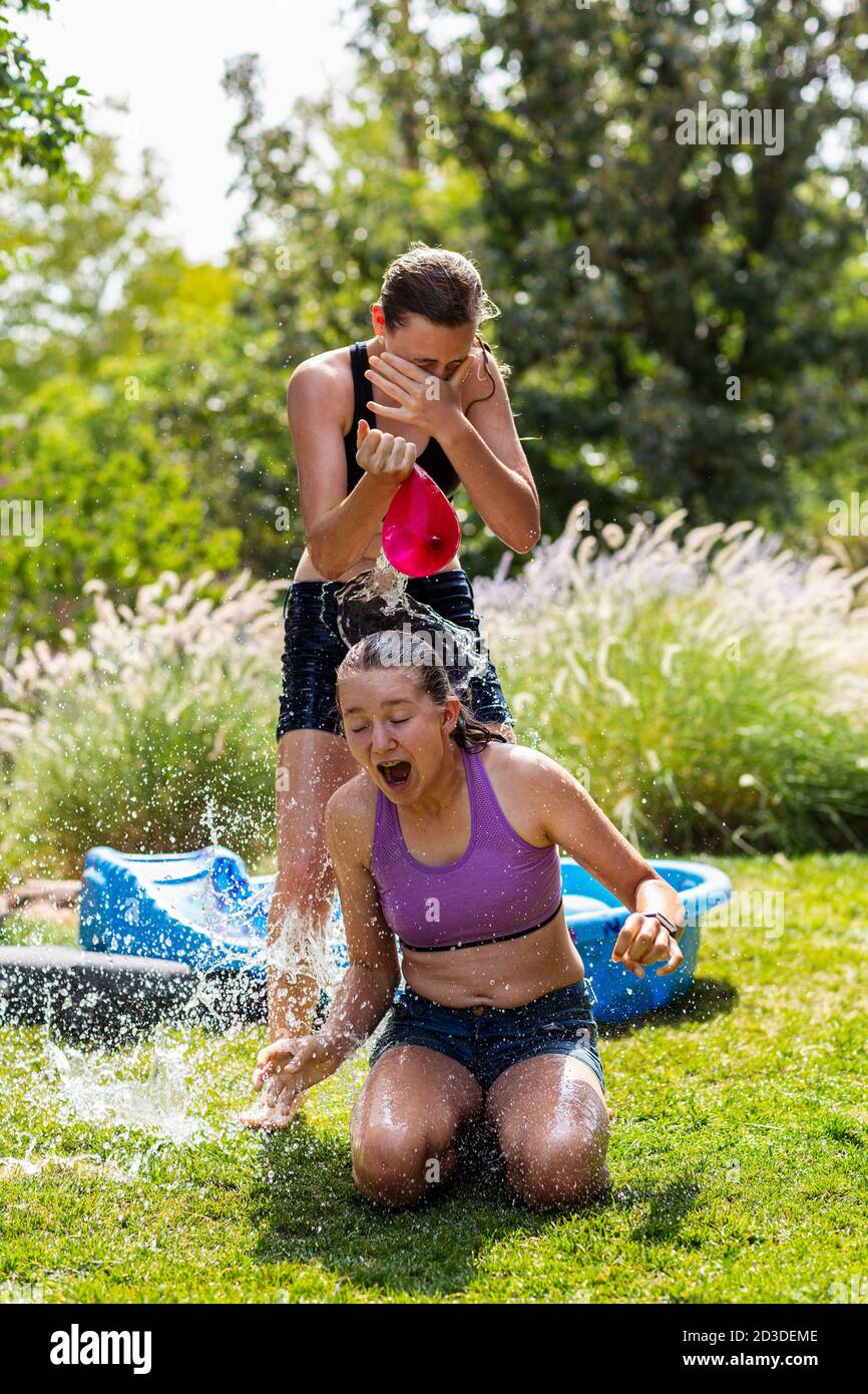 Zwei Mädchen Im Teenageralter Tragen Badekleidung Und Spielen Mit Wasserballons In Einem Garten 