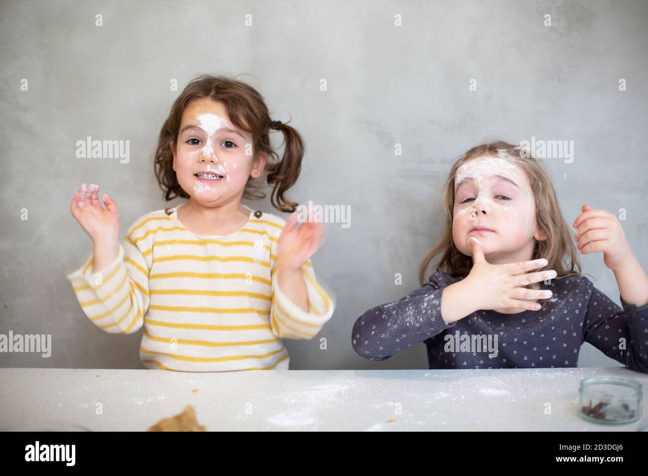 Zwei Mädchen backen Weihnachtsplätzchen, Gesichter mit Mehl und Glasur bedeckt. Stockfoto