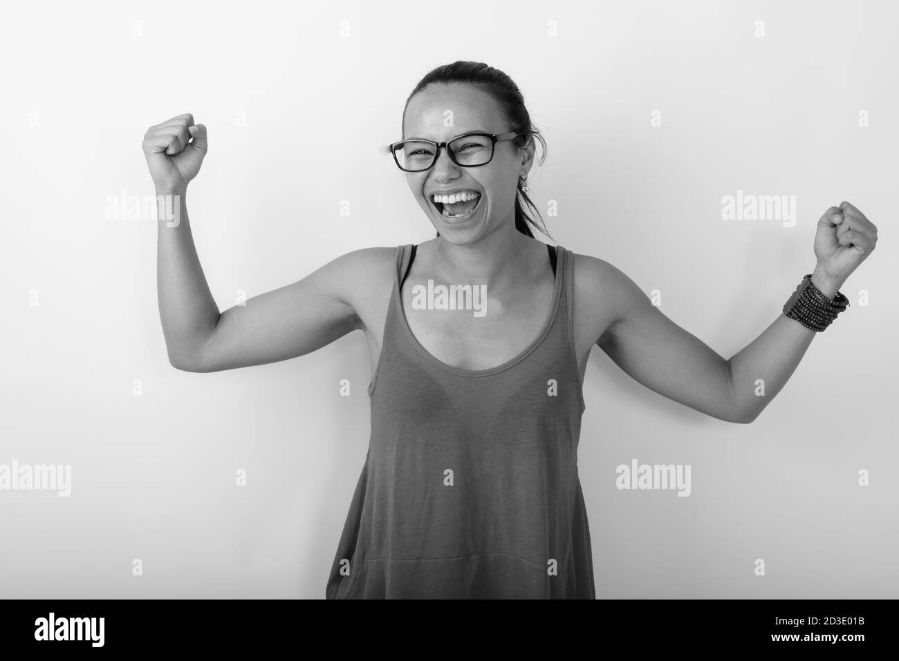 Studioaufnahme der jungen glücklichen asiatischen Frau lächelnd beim Blick Aufgeregt und tragen Brillen Stockfoto