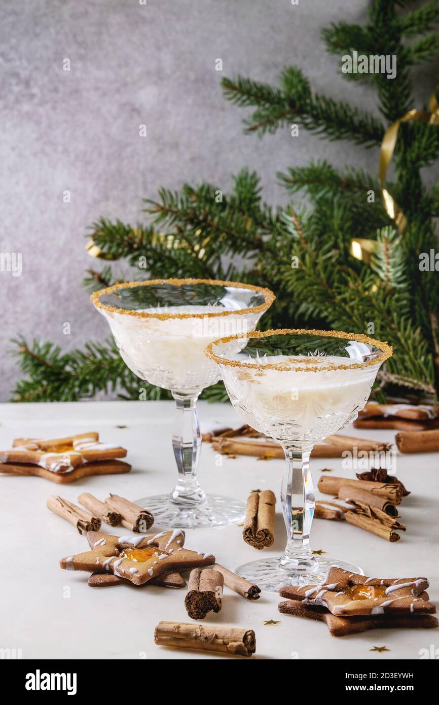 Eierlikör Weihnachten Milch Cocktail, in zwei vintage Crystal serviert Gläser mit SHORTBREAD Stern Sugar Cookies, Zimtstangen, tanne Zweig über Weiß Stockfoto