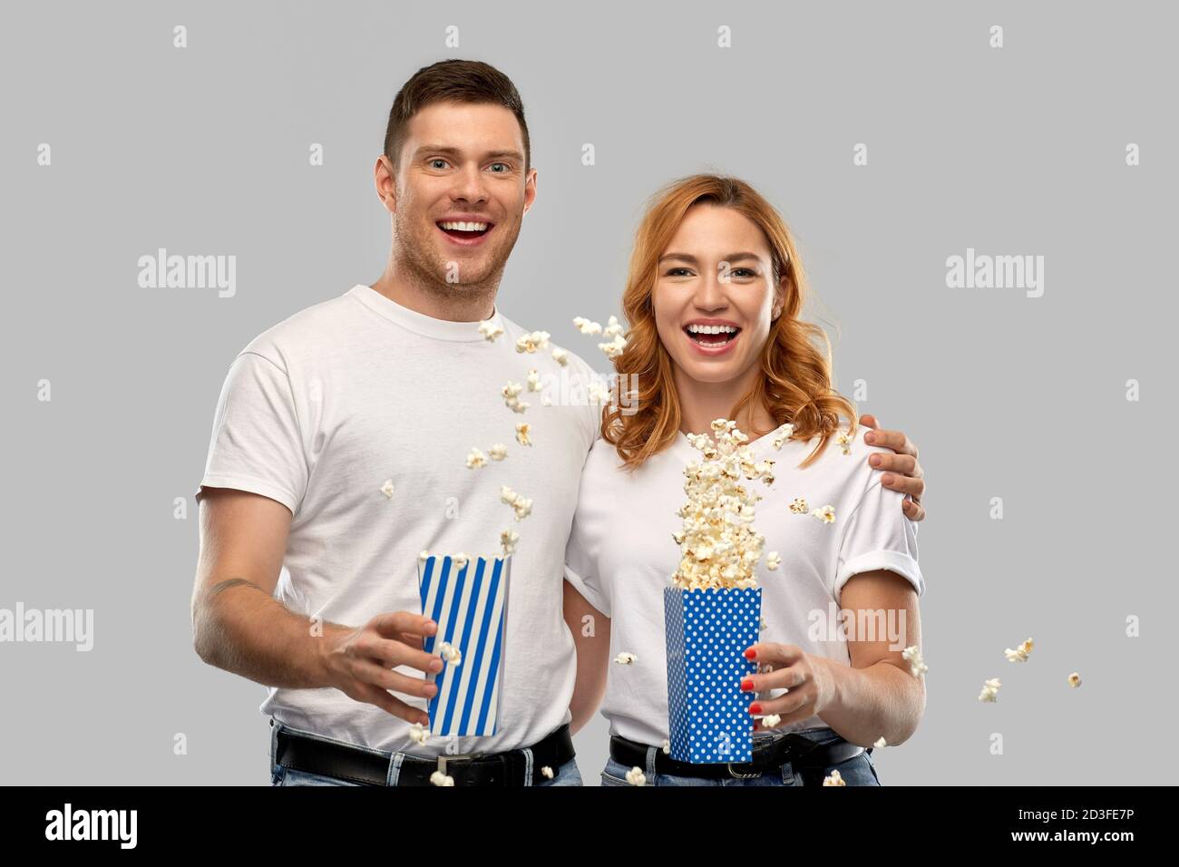 Glückliches Paar in weißen T-Shirts, das Popcorn isst Stockfoto