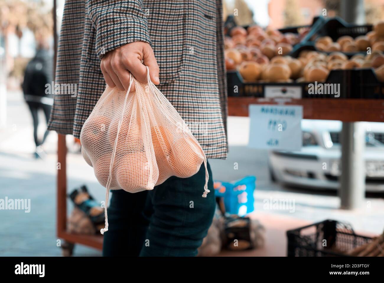 Nahaufnahme eines Mannes, Einkaufen in einem Gemüsehändler oder einem Straßenmarkt, mit einigen textilen wiederverwendbaren Netztüten voller Obst und Gemüse, als Maßnahme zu rot Stockfoto