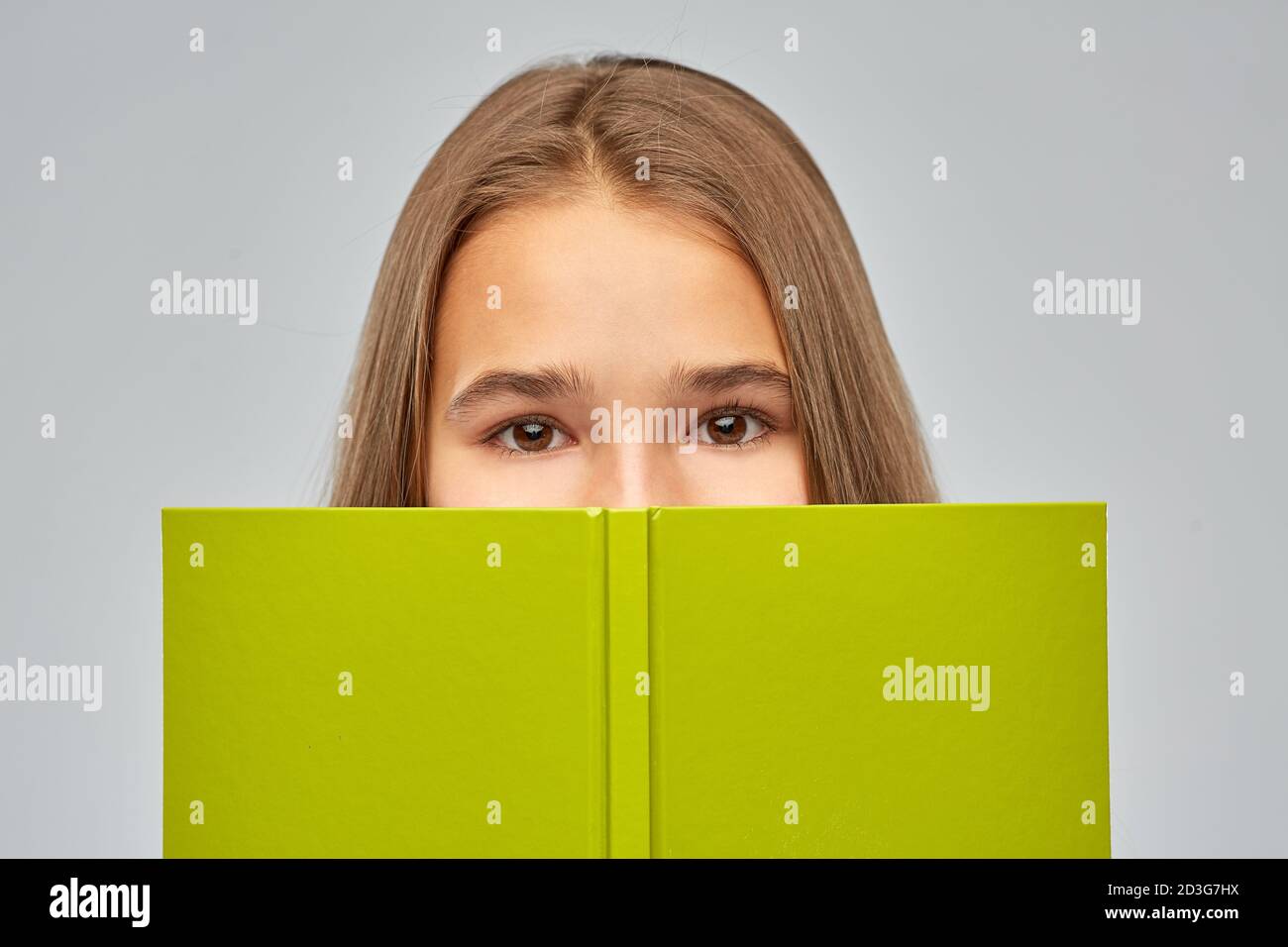 Teenage Student Mädchen versteckt über Buch Stockfoto