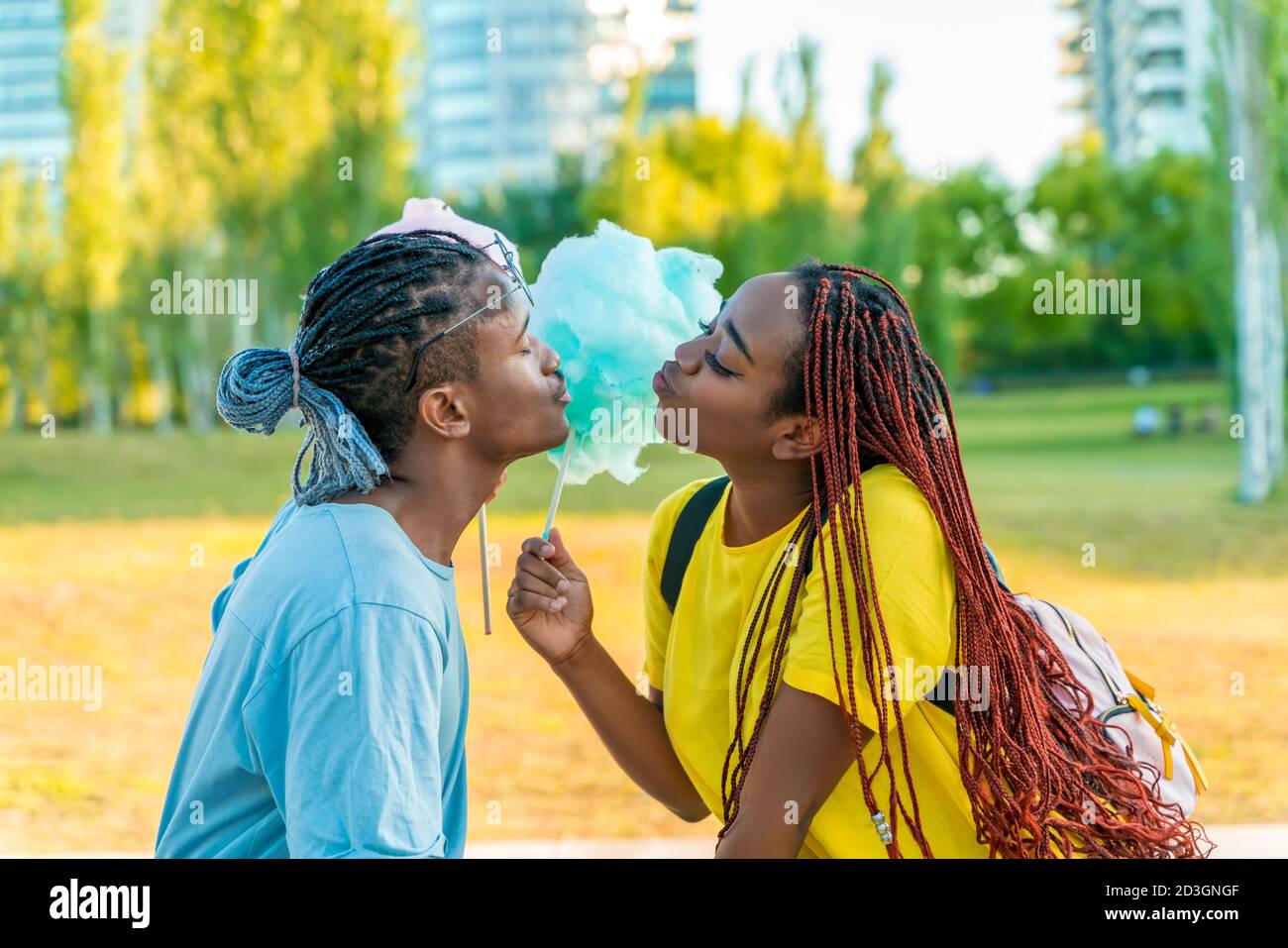 Ein glückliches schwarzes Paar, das bunte Zuckerwatte zusammen in einem Park einer großen Stadt hat. Stockfoto