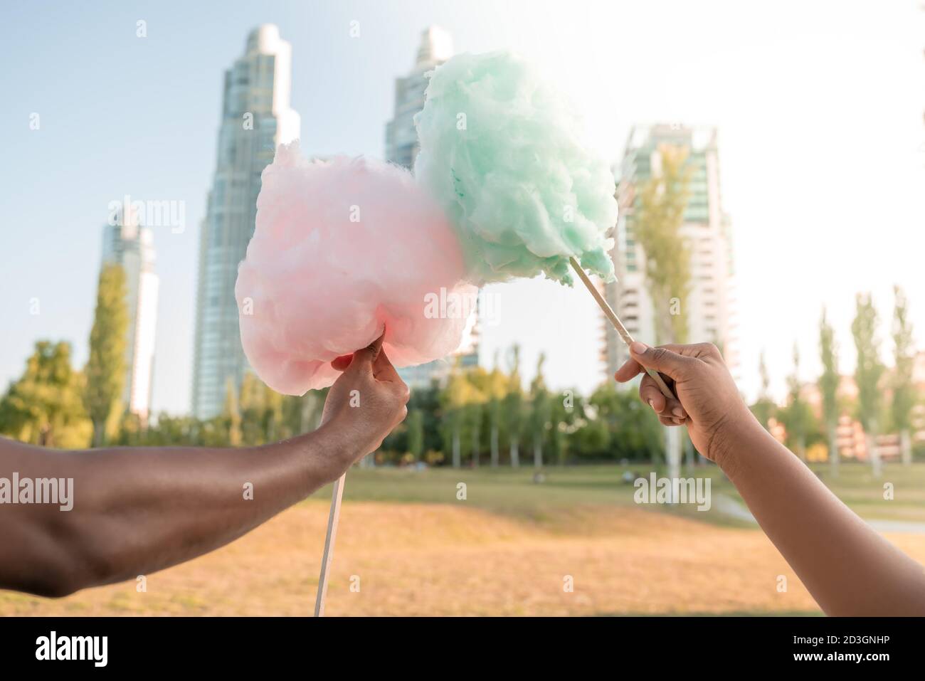 Ein glückliches schwarzes Paar, das bunte Zuckerwatte zusammen in einem Park einer großen Stadt hat. Stockfoto