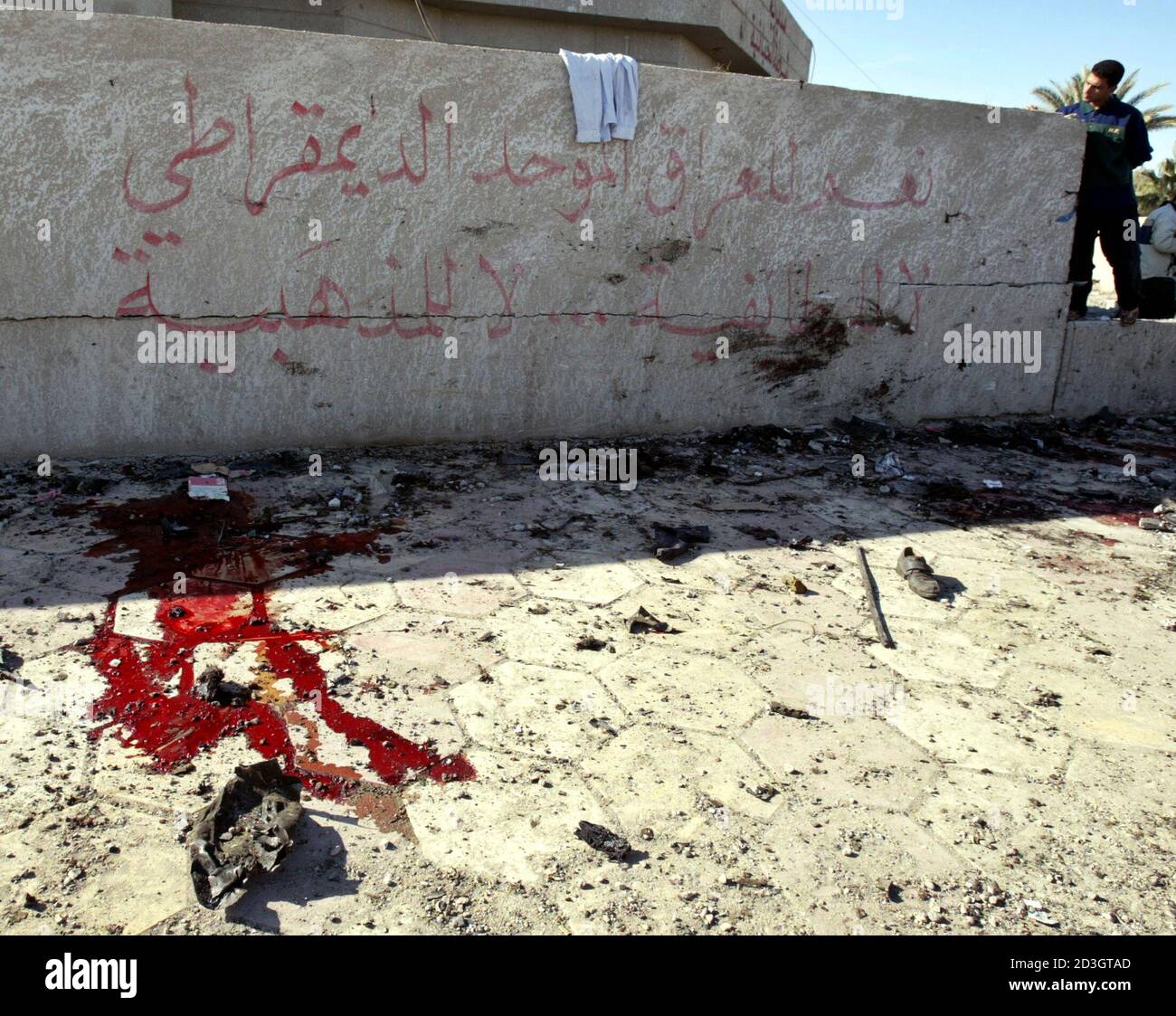 Ein irakischer Mann schaut einer Blutlache neben Graffiti lesen "Ja zum irakischen Freiheit und Demokratie" in Khalidiyah, 60 km (35 Meilen) westlich von Bagdad nach eine Autobombe durch eine Polizeistation 14. Dezember 2003 zerrissen. Mindestens 17 Menschen starben in den neuesten Angriff auf die Kraft im Mittelpunkt Washingtons Pläne macht Iraker übergeben. Stockfoto
