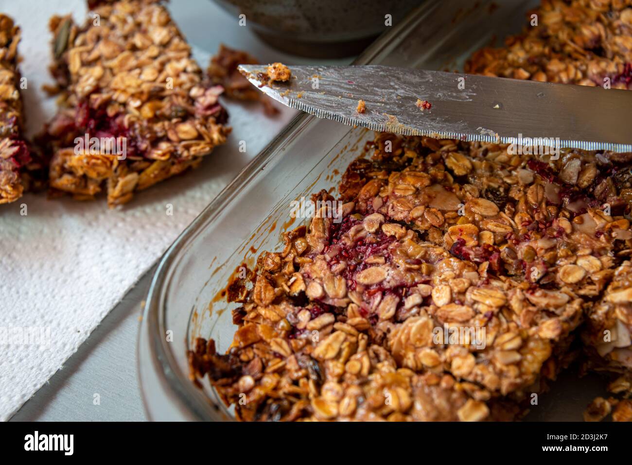 Hausgemachte Müsliriegel in Kochplatte mit Messer. Stockfoto