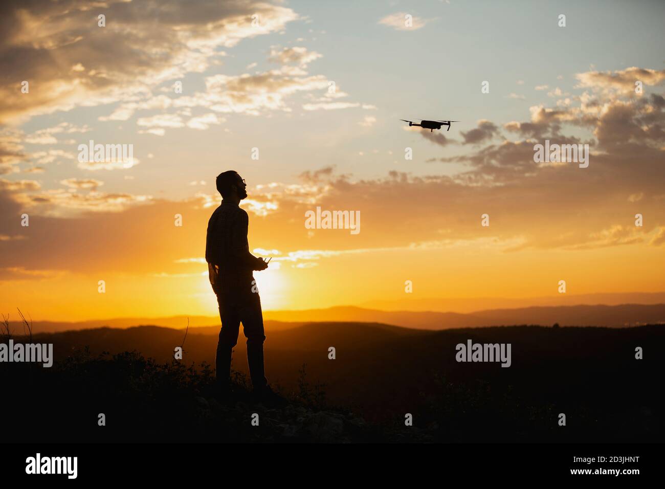Silhouette eines jungen Mannes, der eine Drohne in EINEM BETRIEB Ländliche Lage bei Sonnenuntergang Stockfoto