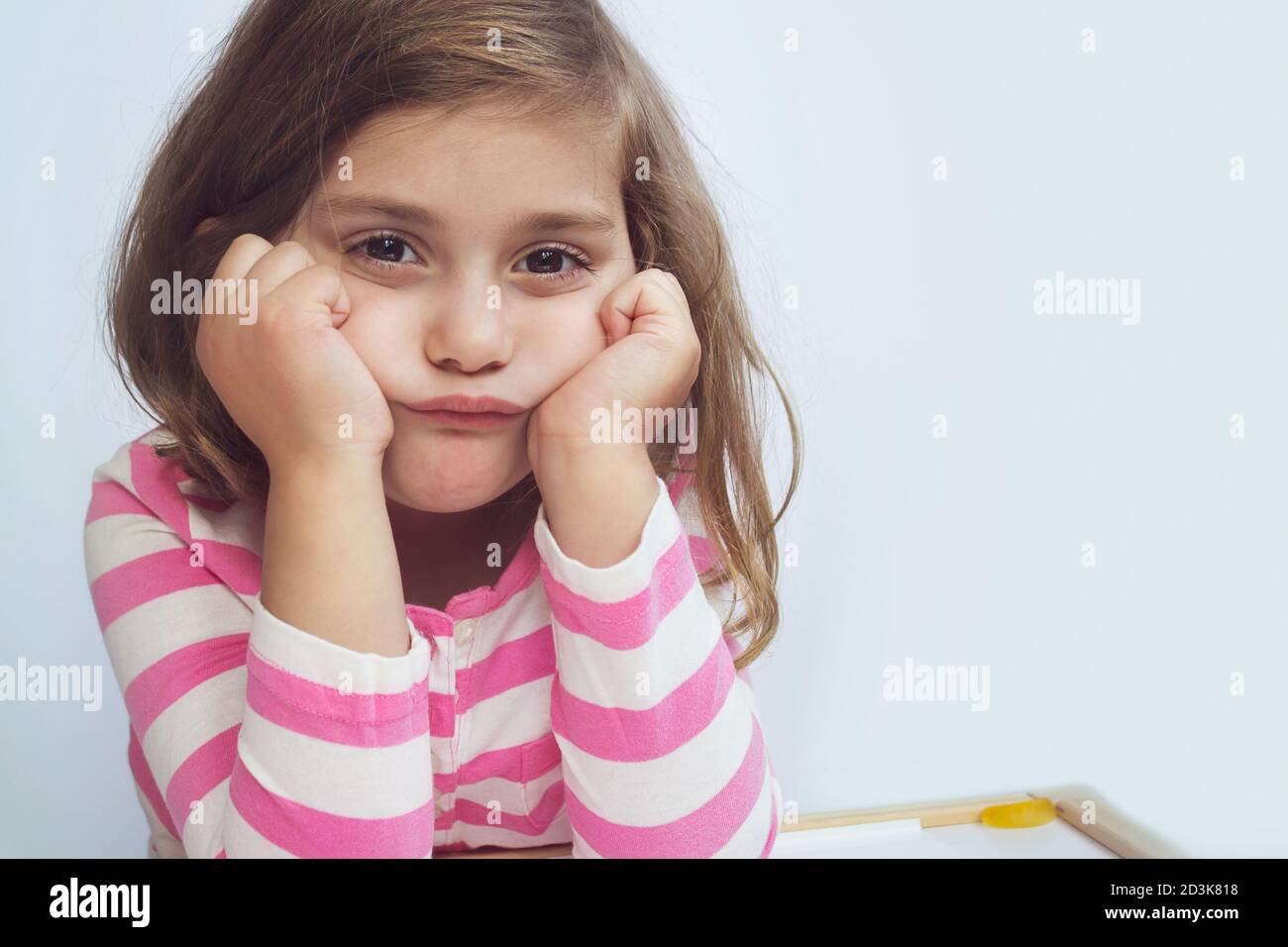 Porträt eines traurigen müde frustriert Mädchen am Tisch sitzen, Mädchen gelangweilt. Lernschwierigkeiten, Bildungskonzept Stockfoto