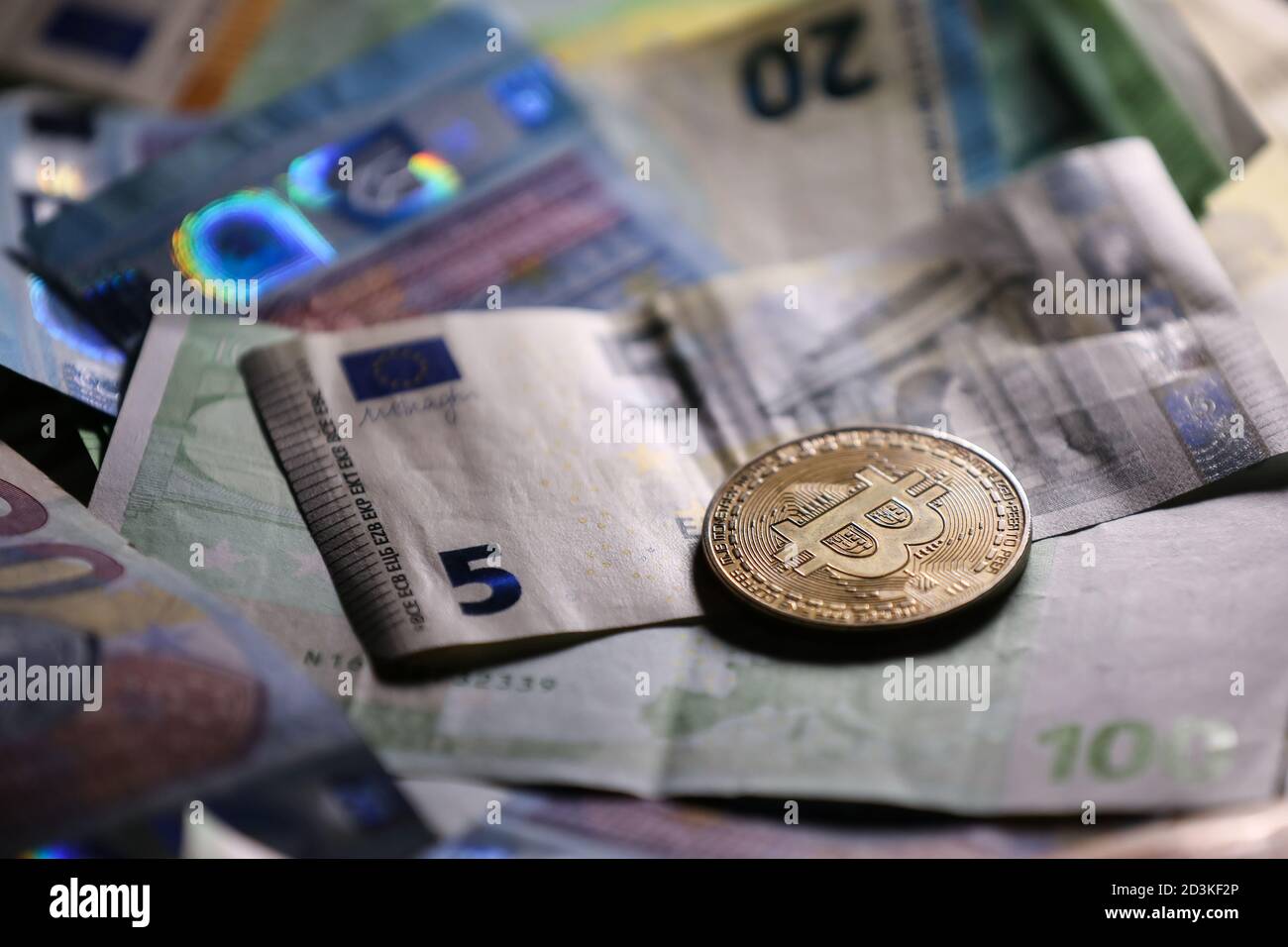 Kleiner Retro-Wecker mit Bitcoin Goldmünze und Euro-Banknoten im Hintergrund. Neuer finanzieller Vermögenswert. Dezentrales Bitcoin-Netzwerk. Stockfoto