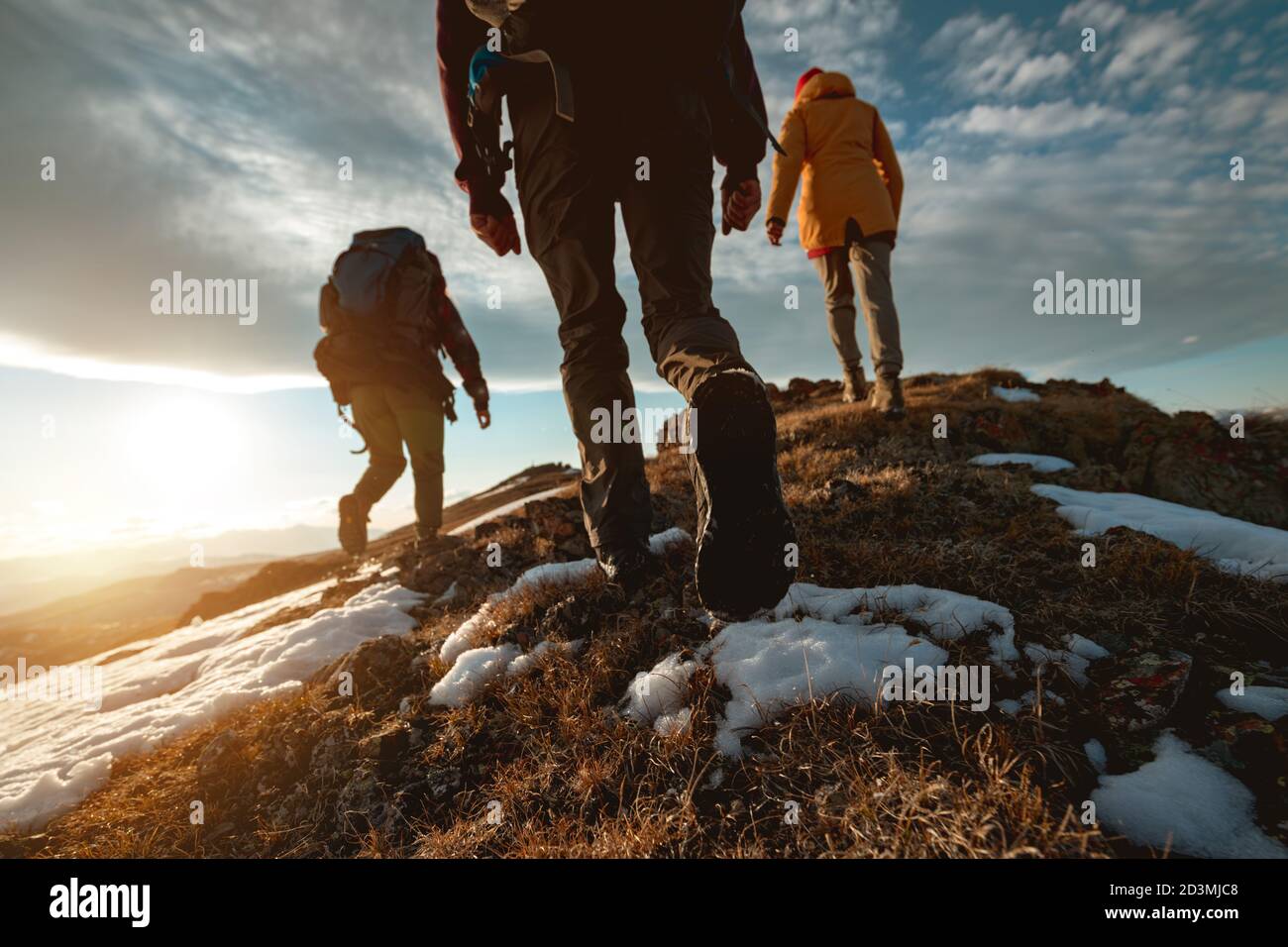 Eine kleine Gruppe von Touristen spaziert bei Sonnenuntergang auf dem Gipfel des Berges. Nahaufnahme des Fotos Stockfoto