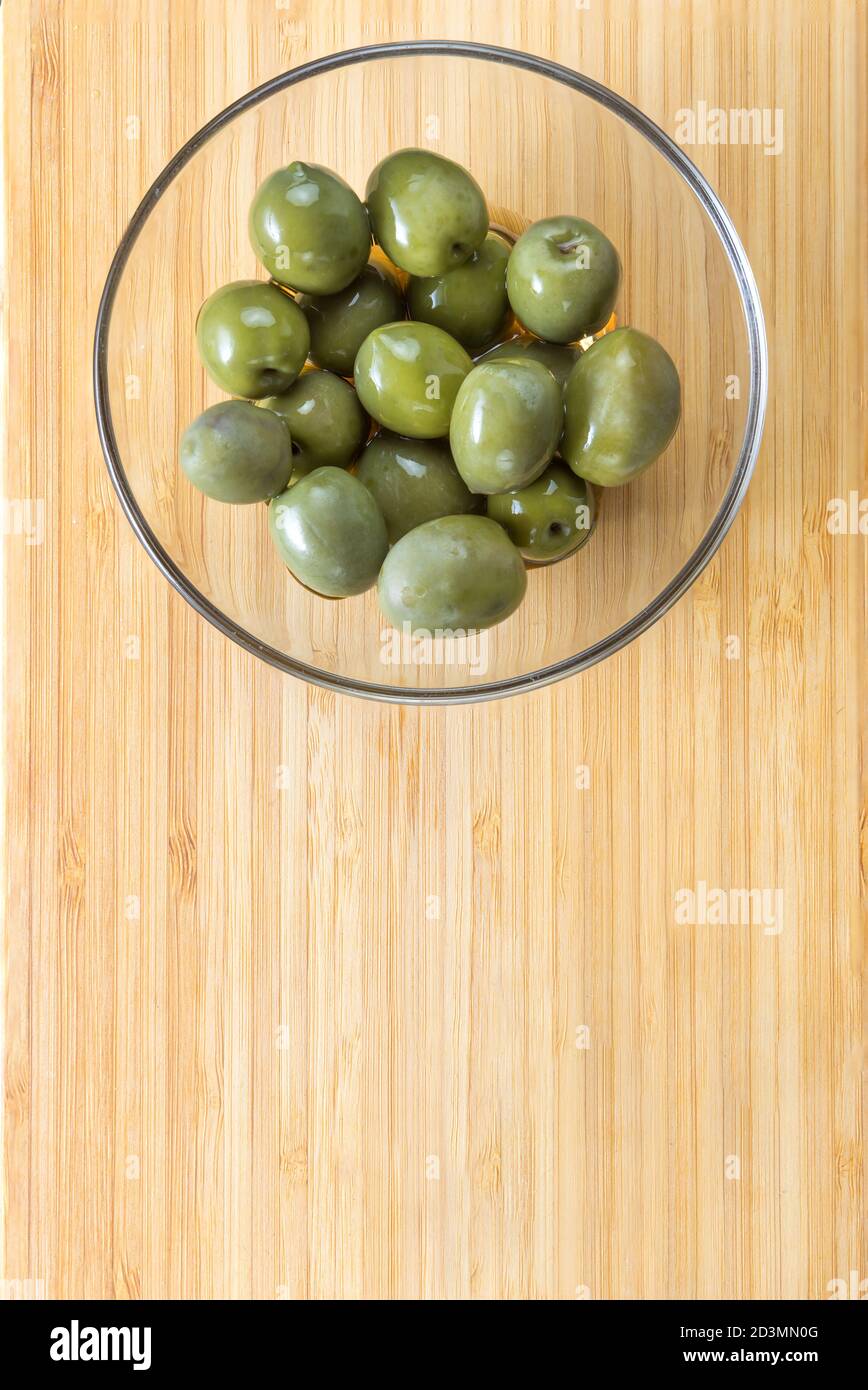 Grüne Oliven in einer Glasplatte auf einem Holzhintergrund Stockfoto