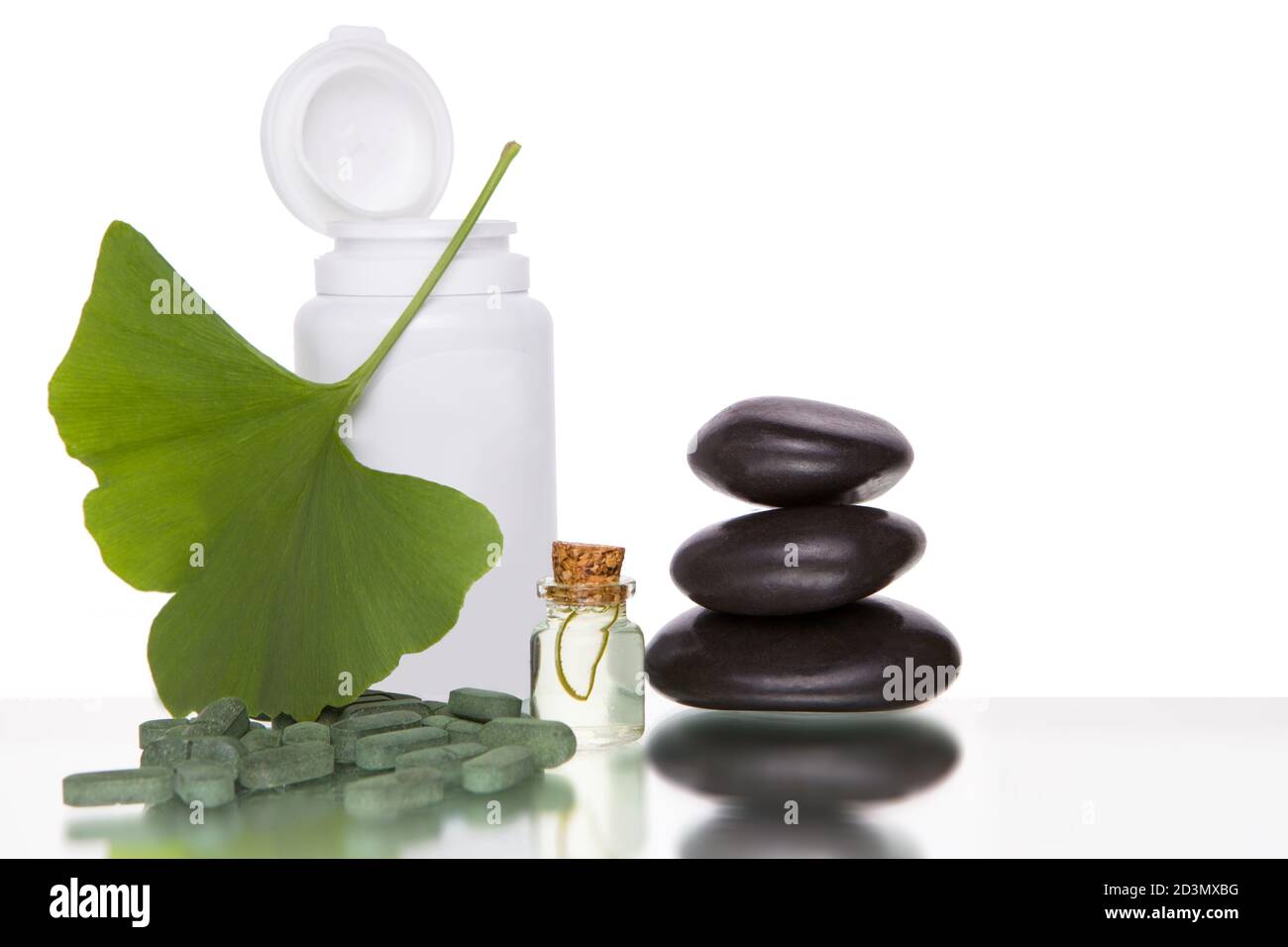 Pillen mit Extrakt aus dem Ginkgo in der Flasche und grünen Blättern isoliert auf weißem Hintergrund. Stockfoto