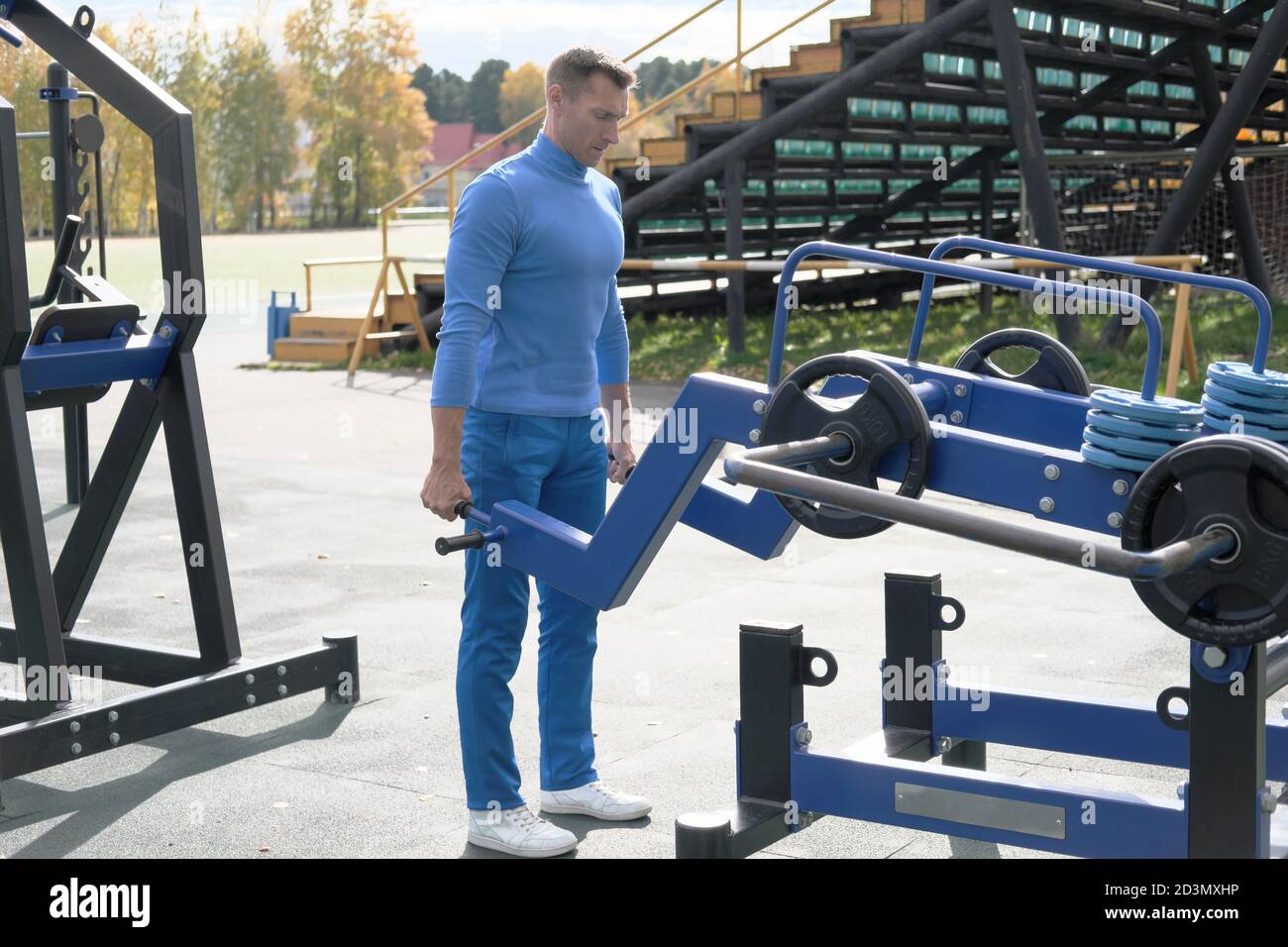 Handsome Mann in Sport-Outfit tun Deadlift mit Street Sport Boden Ausrüstung. Fit und schlank Mann Training auf einem Stadion in der Herbstsaison. Outdoor-Training. Stockfoto