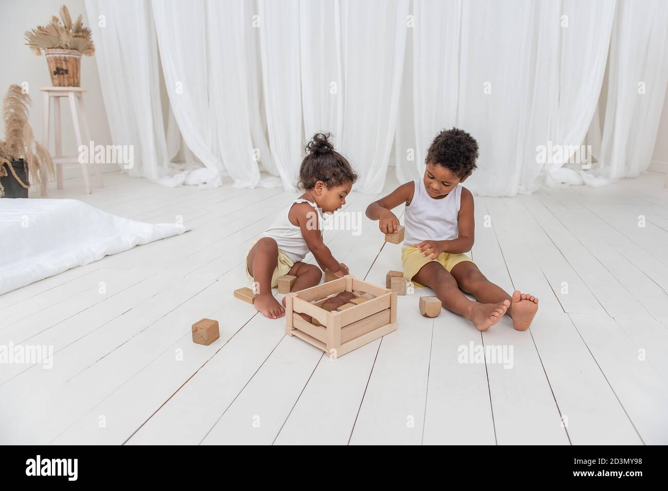 Kleiner Bruder und Schwester African American spielen Häuser mit Holz Öko-Ziegel, bauen und zerstören Türme. Feinmotorik Entwicklung, pädagogische Spiele. Wh Stockfoto