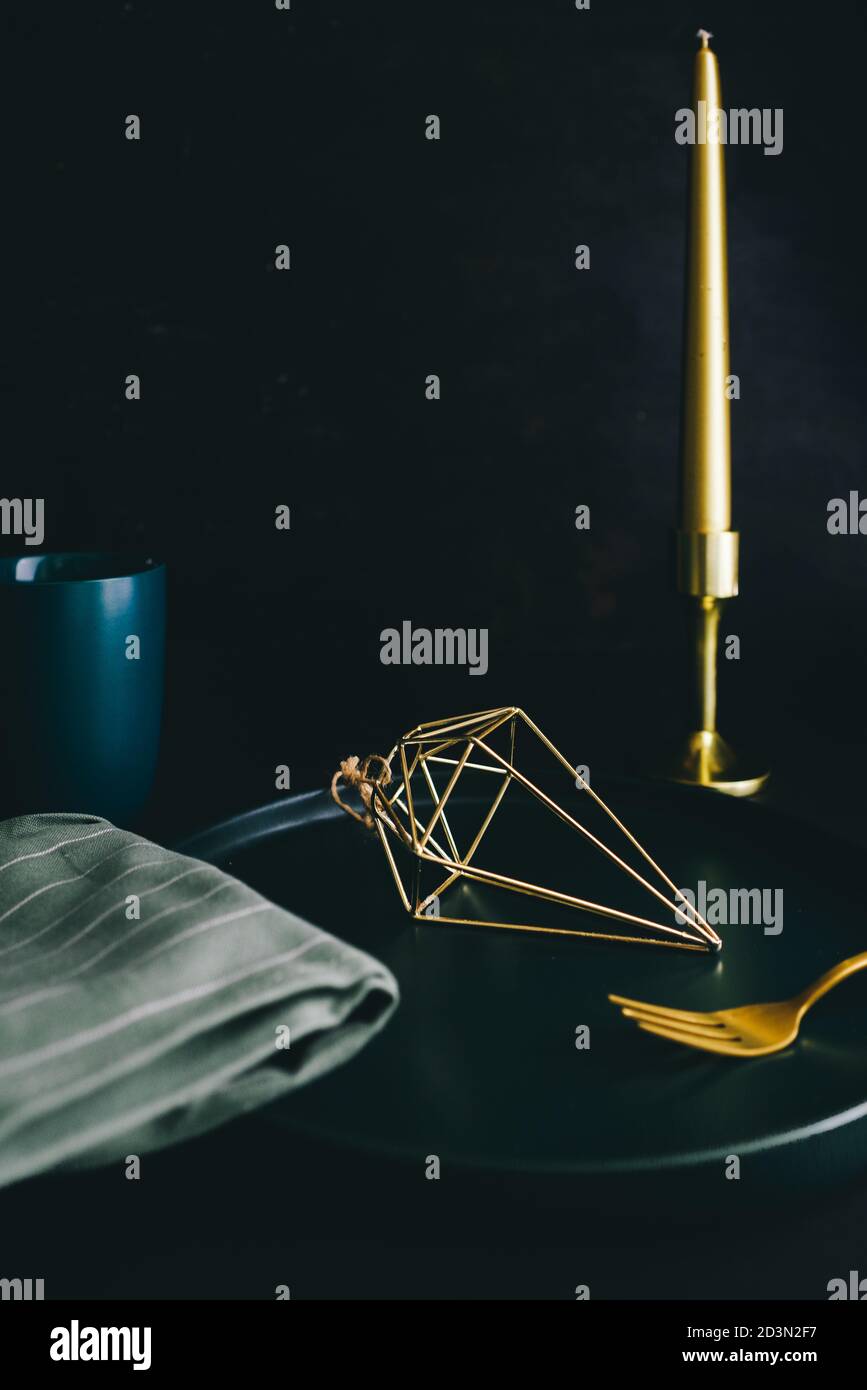 Luxus Stillleben Zusammensetzung, goldene Gegenstände mit Besteck und goldene Dekoration, eine grüne Keramik Schüssel und Tasse, goldene Kerze, Luxus-Artikel zum Verkauf. Stockfoto