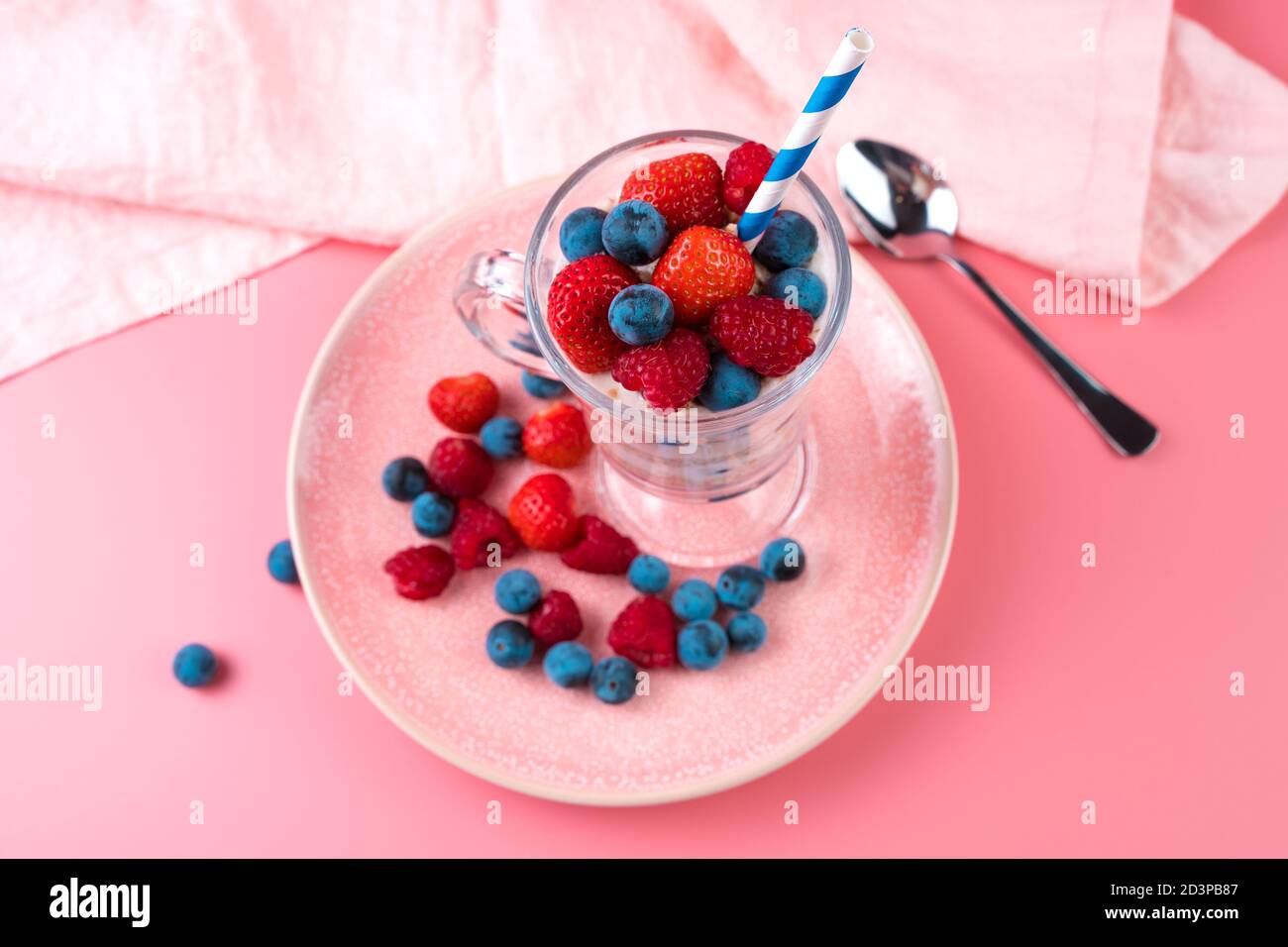 Cremiger Cocktail mit Himbeeren, Erdbeeren und Getreide auf einem weichen rosa Hintergrund. Stockfoto