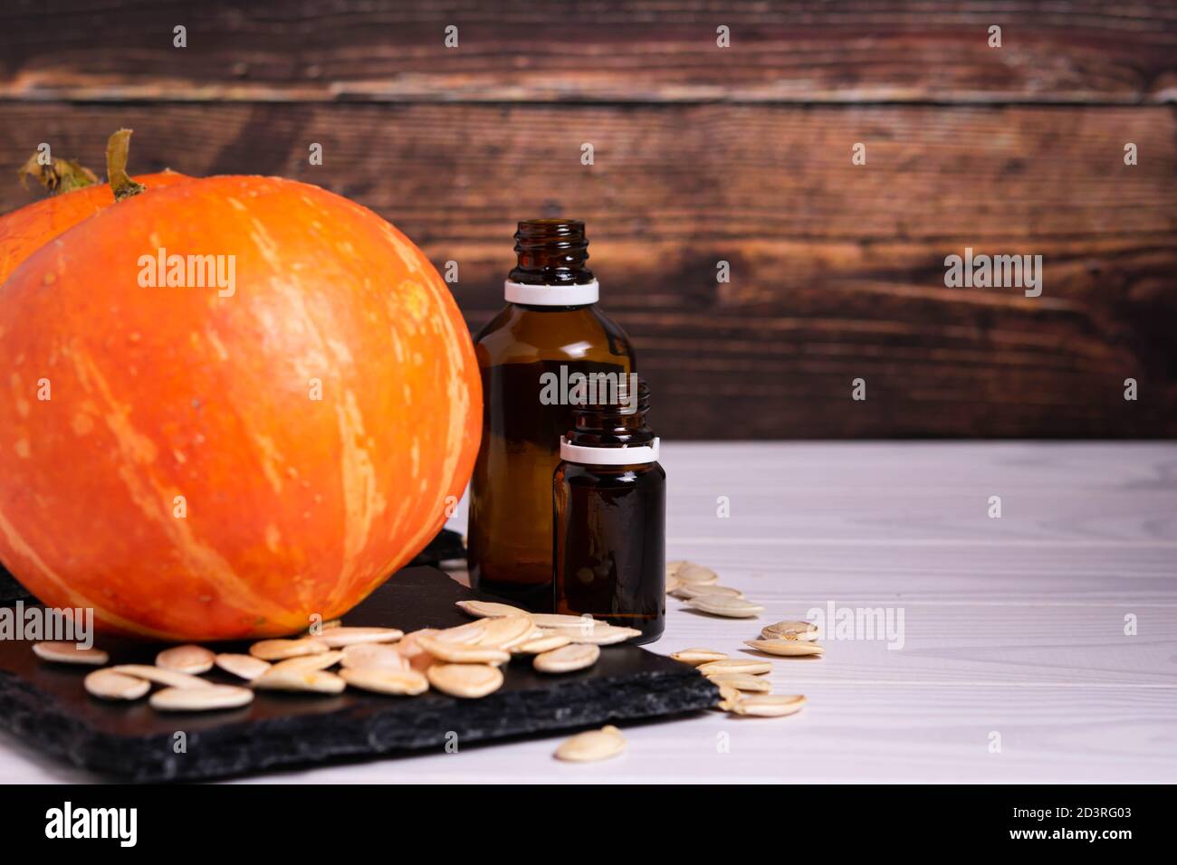 Glasflaschen mit Samen und Kürbis auf Holzgrund Stockfoto