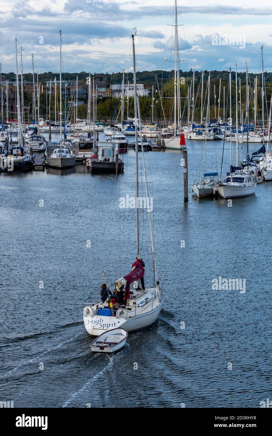 Eine Yacht, die ein zartes oder kleines Boot in die Marina oder den Hafen von lymington im neuen Wald, hampshire, großbritannien, schleppt Stockfoto