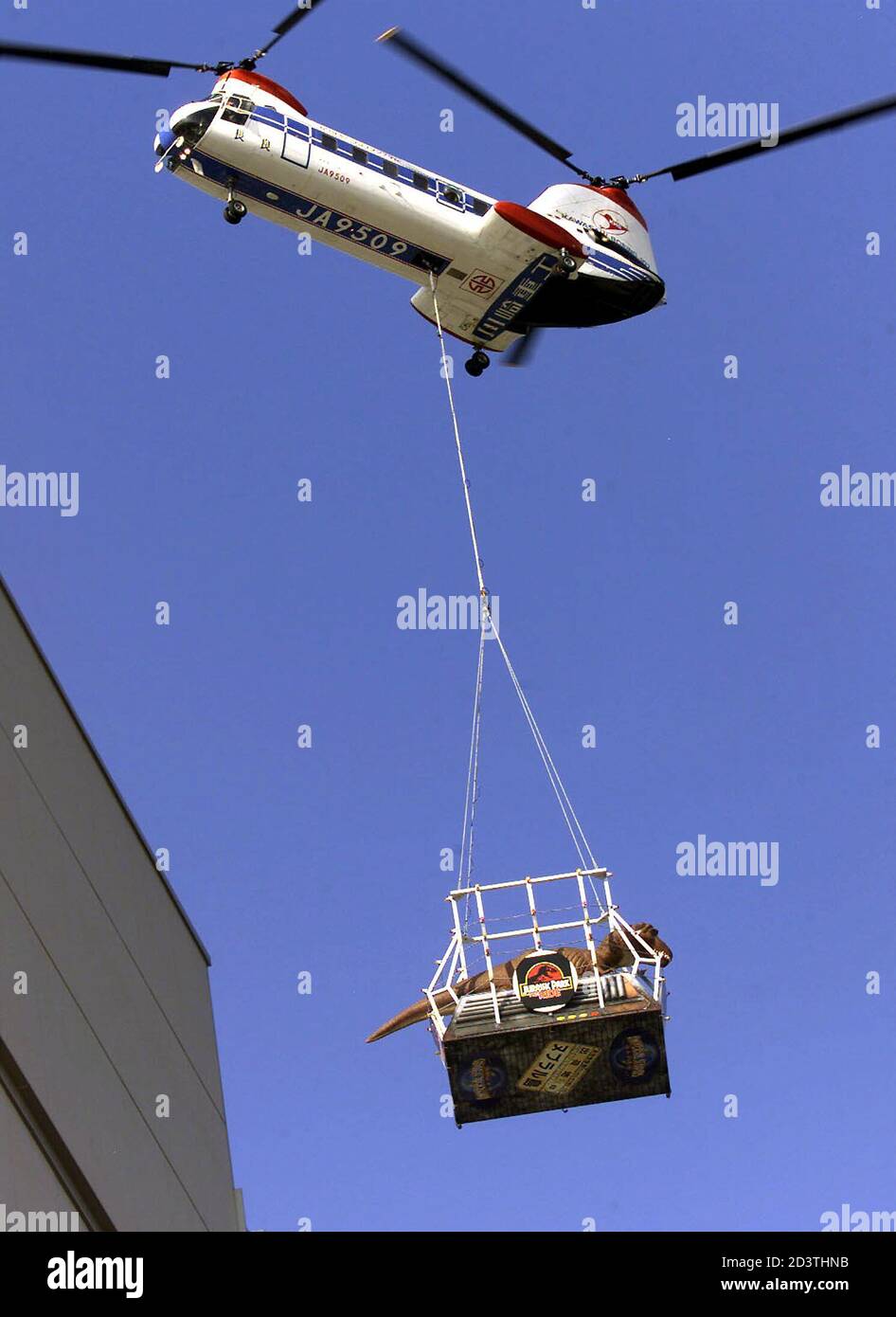 Ein acht Tonnen schweres Tyrannosaurus Rex-Dinosauriermodell wird mit dem  Hubschrauber über ein Gebäude im Jurassic Park in den Universal Studios  Japan geflogen, als es von Los Angeles aus über den Hafen von