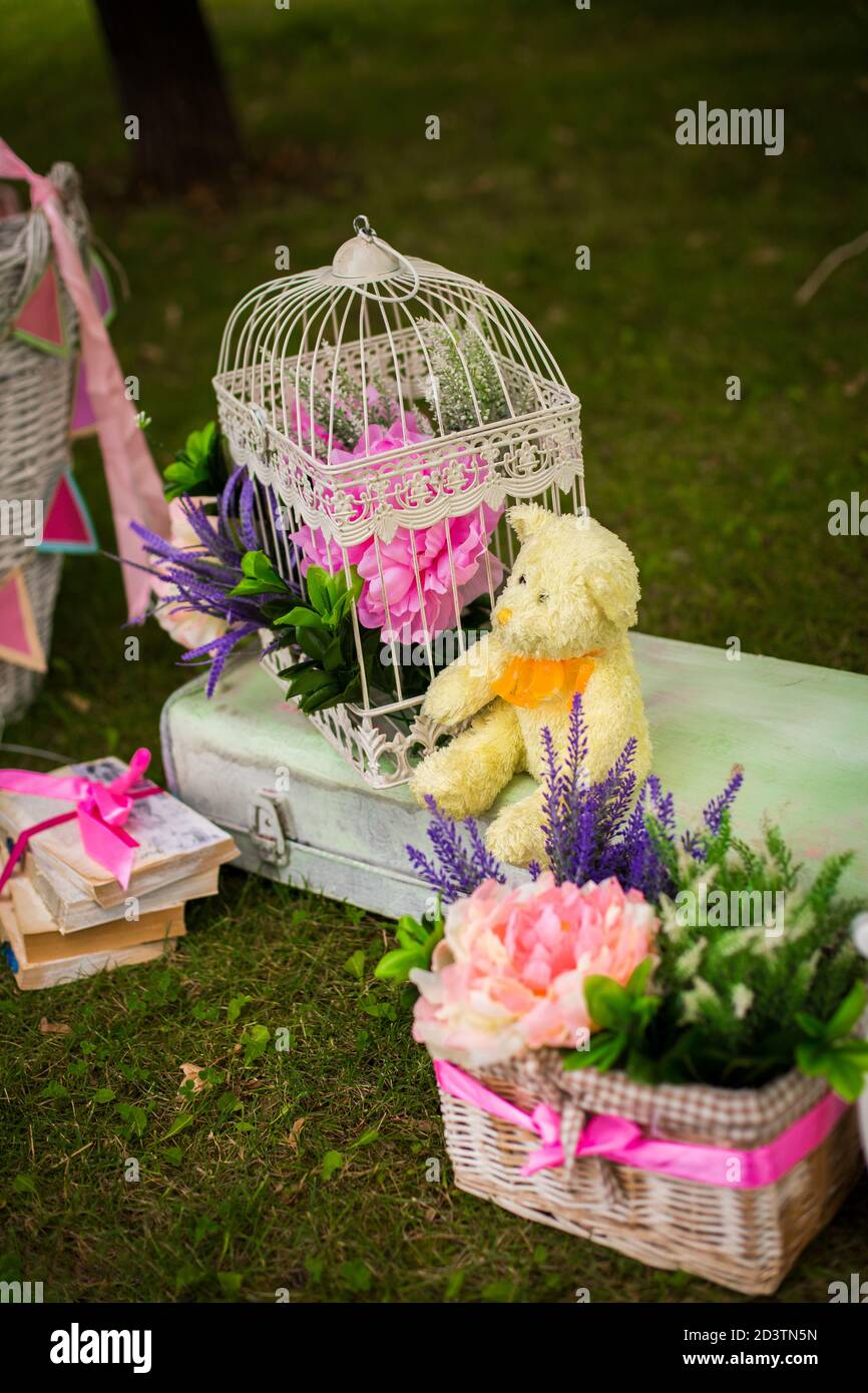 Straßendekorationen für eine Kinderparty. Retro Koffer mit Blumen mit einem Teddybären in einem grünen Park. Party auf der Straße. Stockfoto