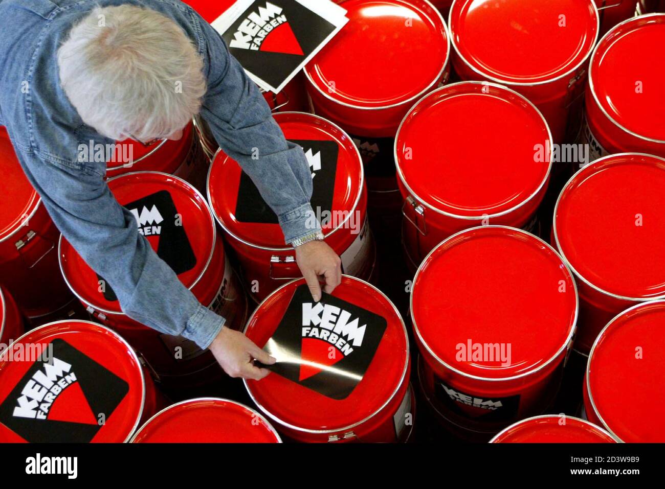 Ein Mitarbeiter der deutschen Malerei Maker Keimfarben behebt Unternehmen  Aufkleber auf Eimer voller Farbe in Diedorf in der Nähe der bayerischen  Stadt Augsburg 24. April 2003. [Das Unternehmen, das Farbe für das