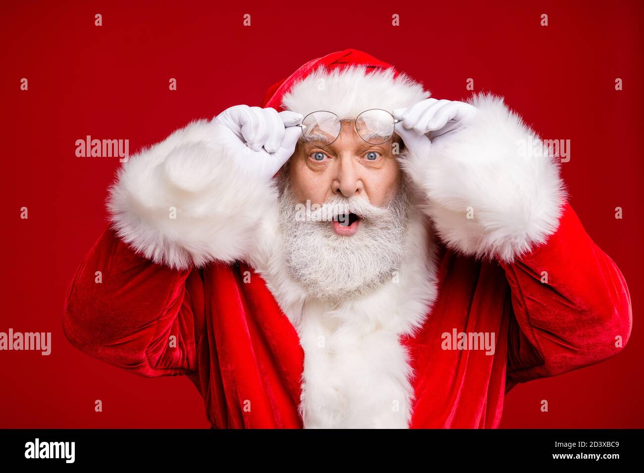 Foto von Rentner alten Mann grauen Bart aufgeregt Look halten Brillen offen Mund Schock sehen weiblich gleichen Outfit tragen santa Kostüm Mantel Brille Kopfbedeckung Stockfoto
