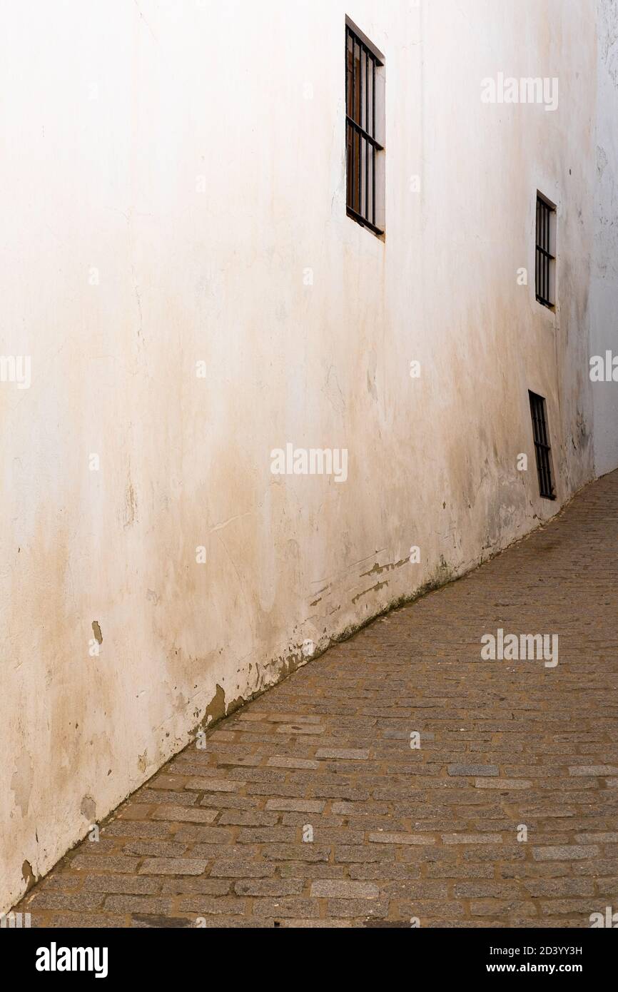 Alte Hausmauer mit drei Fenstern auf einer schmalen Straße In Andalusien Stockfoto