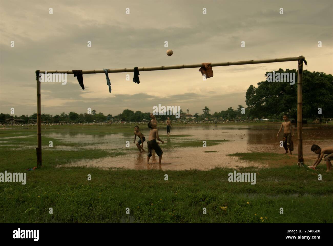 Kinder spielen Fußball auf einem teilweise überfluteten Feld, das sich zwischen zwei öffentlichen Friedhöfen in Pondok Kelapa, Jakarta, Indonesien, befindet. Stockfoto