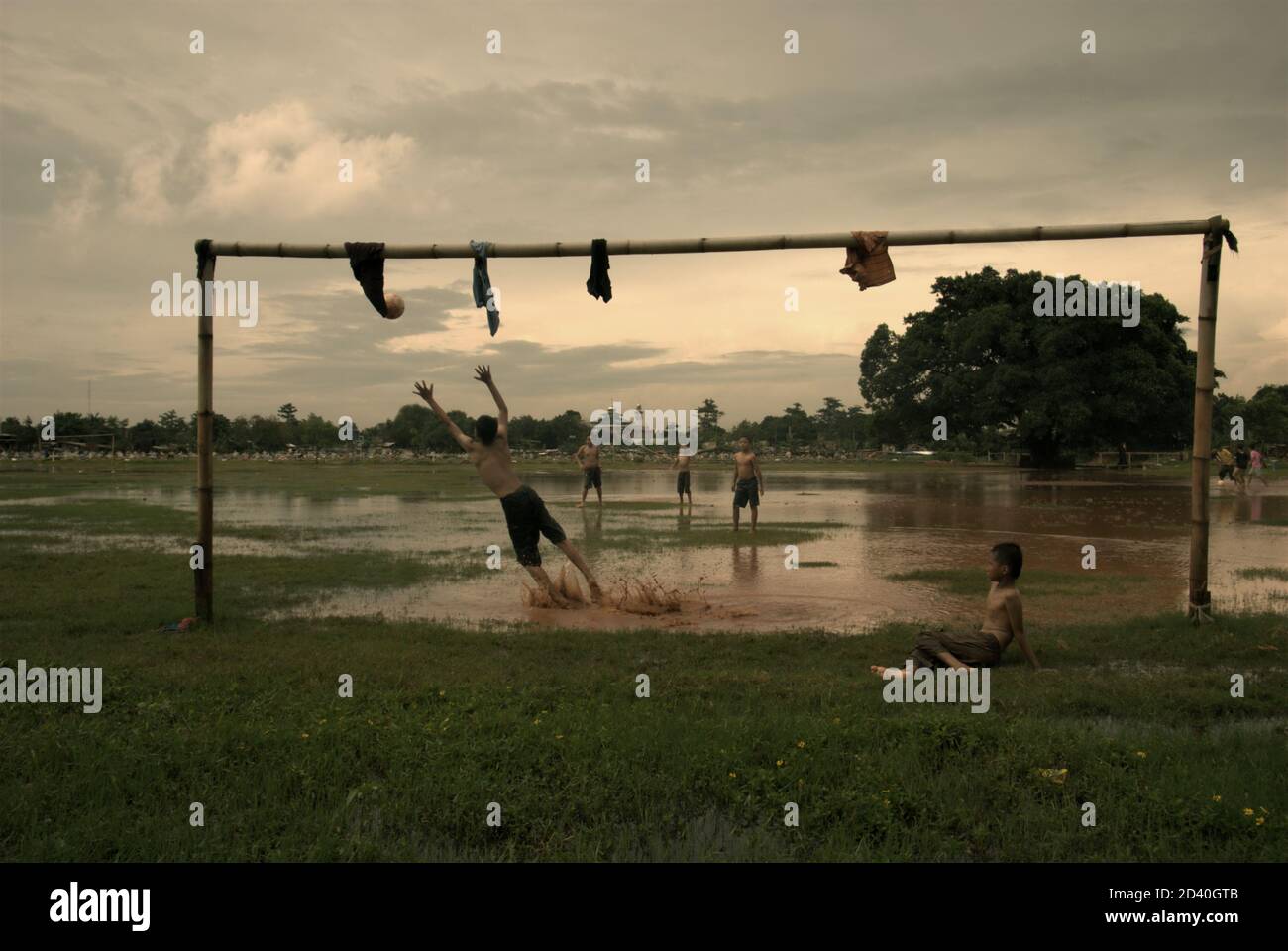 Kinder spielen Fußball auf einem teilweise überfluteten Feld, das sich zwischen zwei öffentlichen Friedhöfen in Pondok Kelapa, Jakarta, Indonesien, befindet. Stockfoto