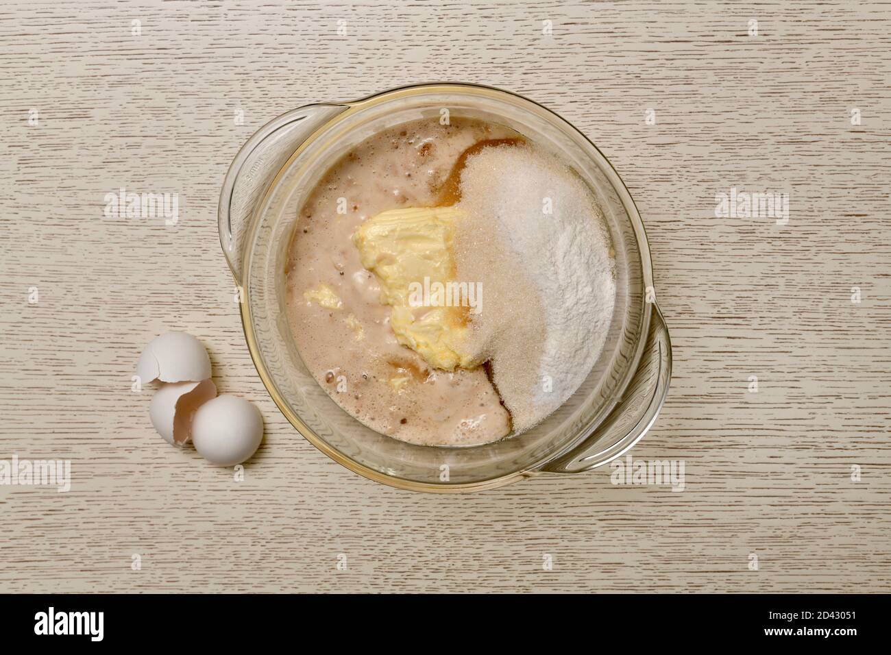 Eine Mischung aus Milch, Eiern, Butter, Zucker, Salz, Backpulver, Vanillin und Hefe in einem durchsichtigen Glaskasserolle. Stockfoto