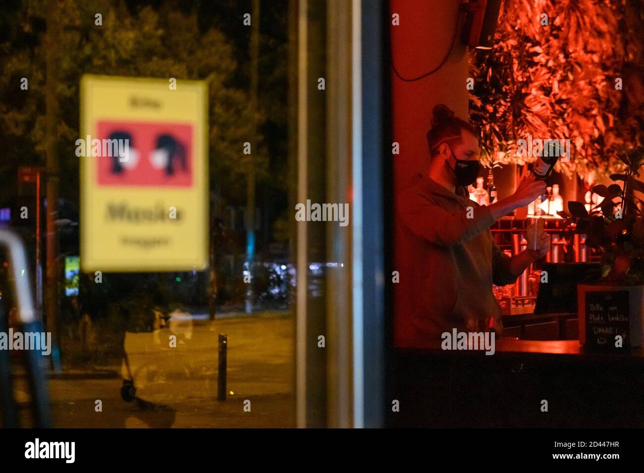 Hamburg, Deutschland. Okt. 2020. ABBILDUNG - Barkeeper Ron steht hinter der Theke einer Bar im Schanzenviertel mit Mund- und Nasenschutz, während an der Eingangstür ein Schild mit Symbolen und der Aufschrift 'Bitte Maske tragen' zu sehen ist. Für den Hamburger Virologen Schmidt-Chanasit sind strengere Koronamaßnahmen mit bundesweiten Öffnungszeiten für Bars und Restaurants, wie in Berlin in der Hansestadt, unproduktiv. (To dpa 'Virologe Schmidt-Chanasit hält Corona-Regel ausreichend') Quelle: Jonas Walzberg/dpa/Alamy Live News Stockfoto