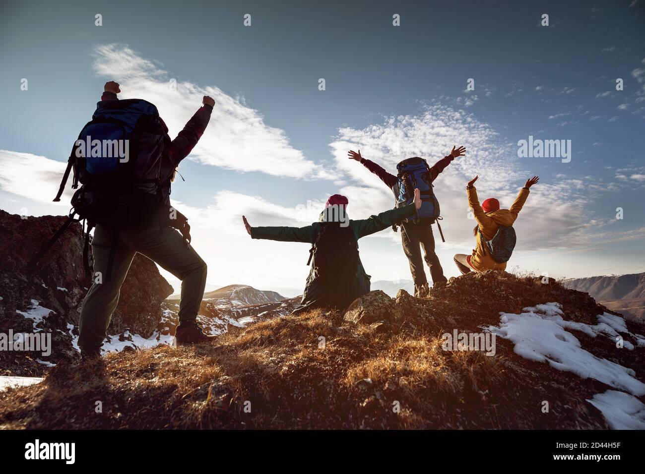 Vier glückliche Wanderer stehen in Siegerposen am Berggipfel Bei Sonnenuntergang Stockfoto