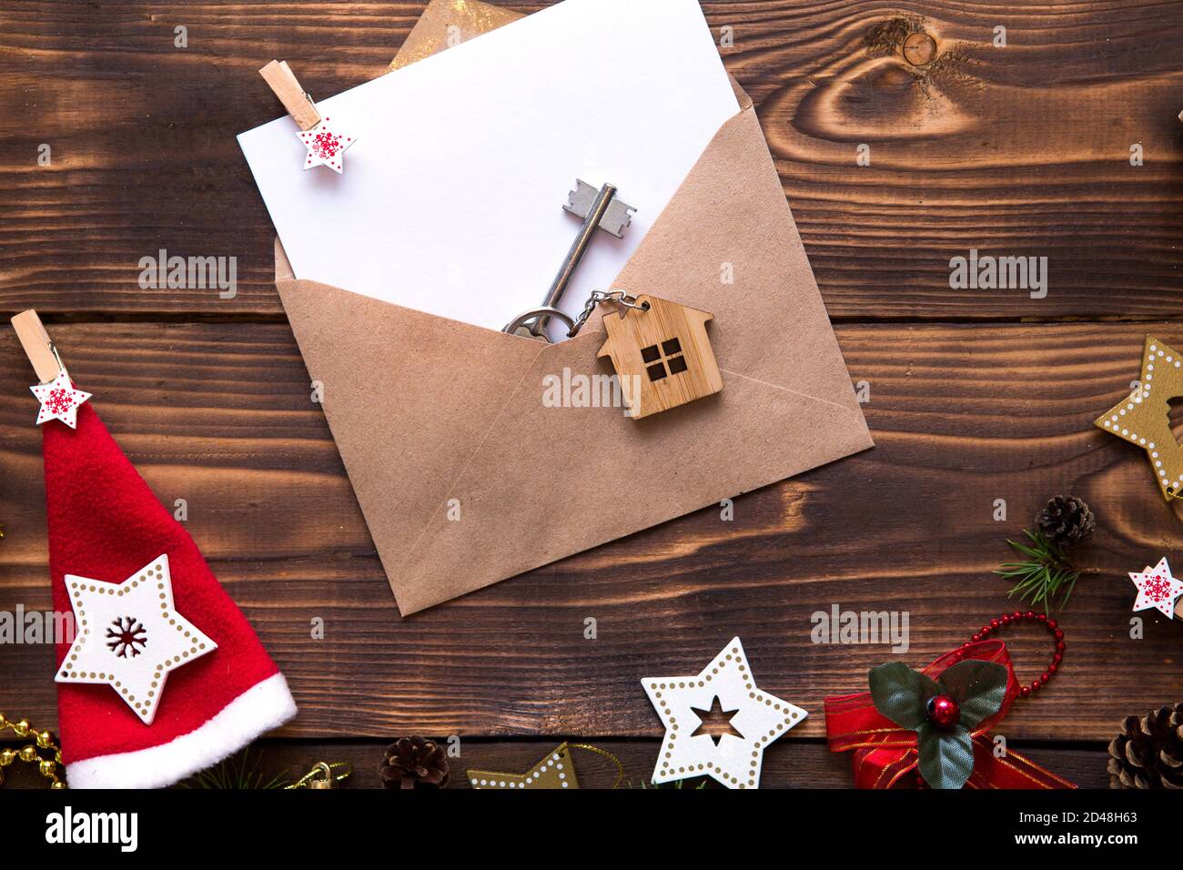 Weihnachtswohnung lag auf einem hölzernen Hintergrund mit Schlüsseln zu neuem Haus in der Mitte mit einem Umschlag mit einem Zettel. Neues Jahr, Übertragung, Aktien der Mo Stockfoto
