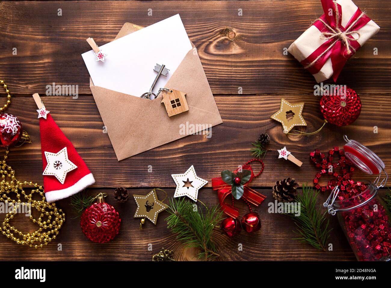 Weihnachtswohnung lag auf einem hölzernen Hintergrund mit Schlüsseln zu neuem Haus in der Mitte mit einem Umschlag mit einem Zettel. Neues Jahr, Übertragung, Aktien der Mo Stockfoto
