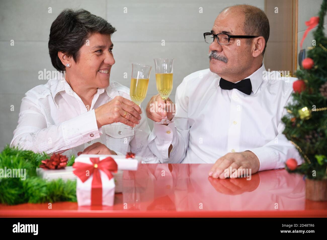 Seniorenpaar feiert weihnachten klirrrende Gläser Champagner. Weihnachtsfeier Konzept. Stockfoto
