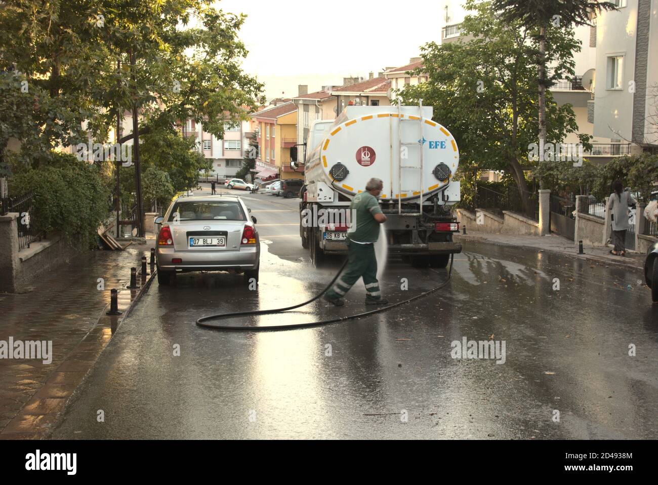 Ankara/Turkey - 28/09/2020 männlicher Arbeiter, der eine Straße wascht und desinfiziert Mit einem Schlauch, der an den Behälter angeschlossen ist Stockfoto