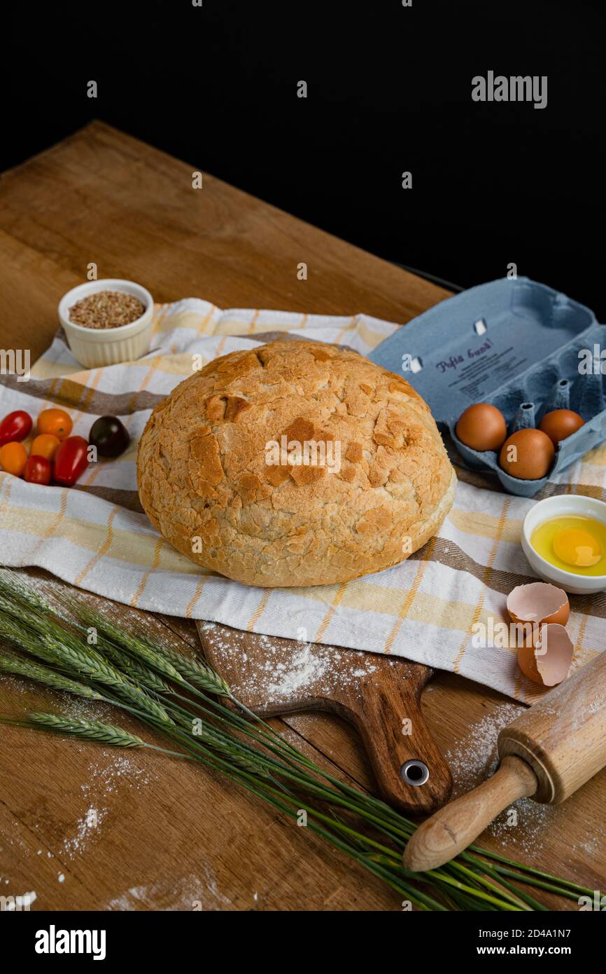 Frisches Brot zusammen mit Tomaten und Eiern auf ein Handtuch gelegt. Bäckerei - Gold rustikale knusprige Brote. Stillleben von oben (Draufsicht, Stockfoto