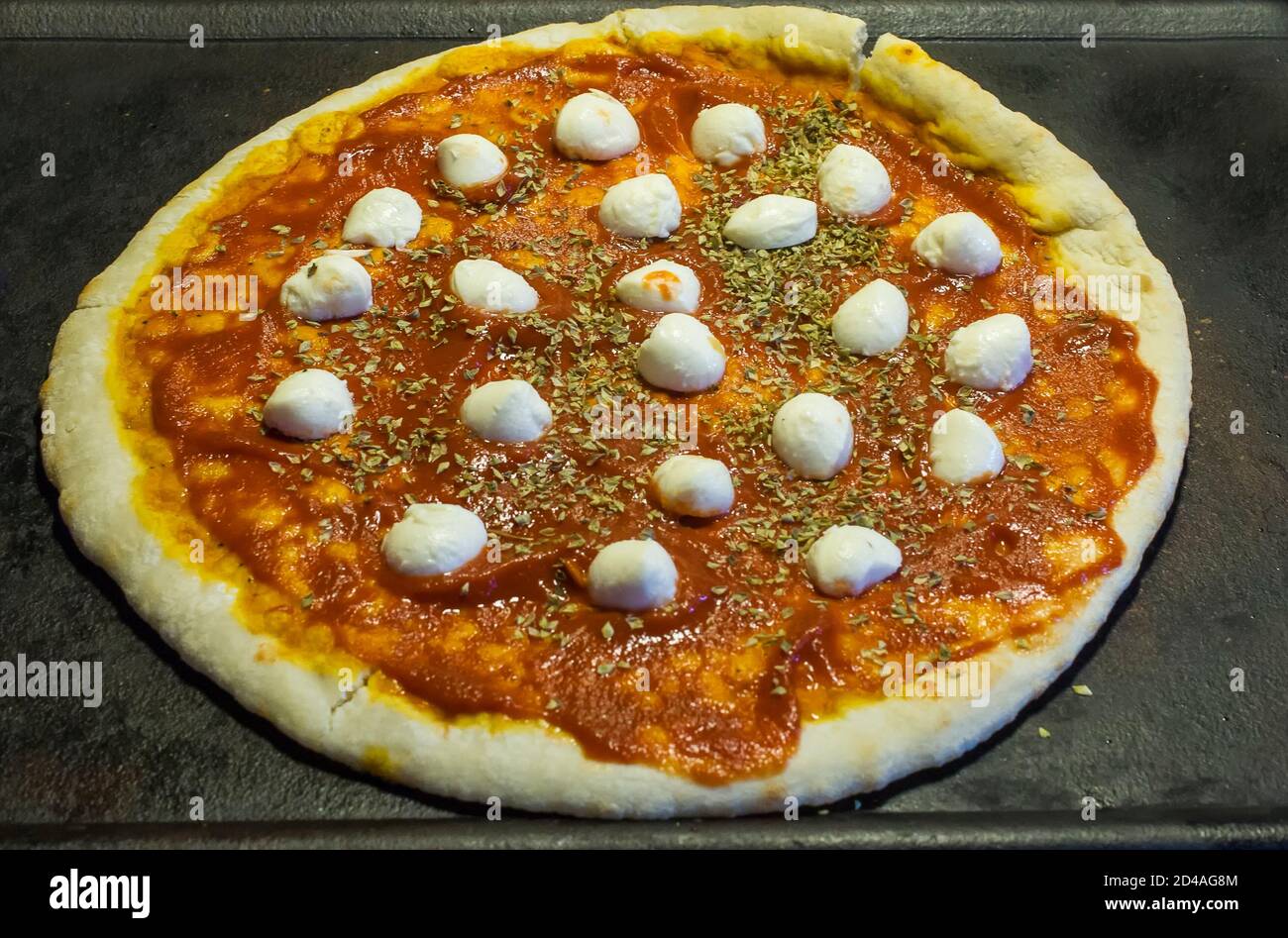 Pizza auf Schiefer mit Tomatensauce, Mozzarella und Oregano Stockfoto