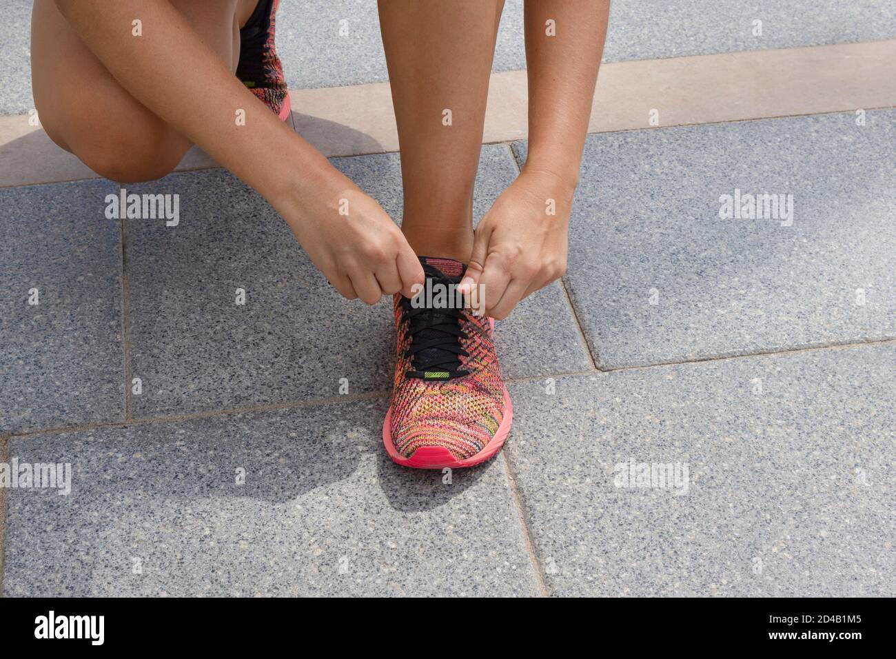 Sportliche junge Frau, die die Schnürsenkel vor dem Laufen oder Joggen bindet.Konzept von Sport und gesunder Lebensweise. Stockfoto