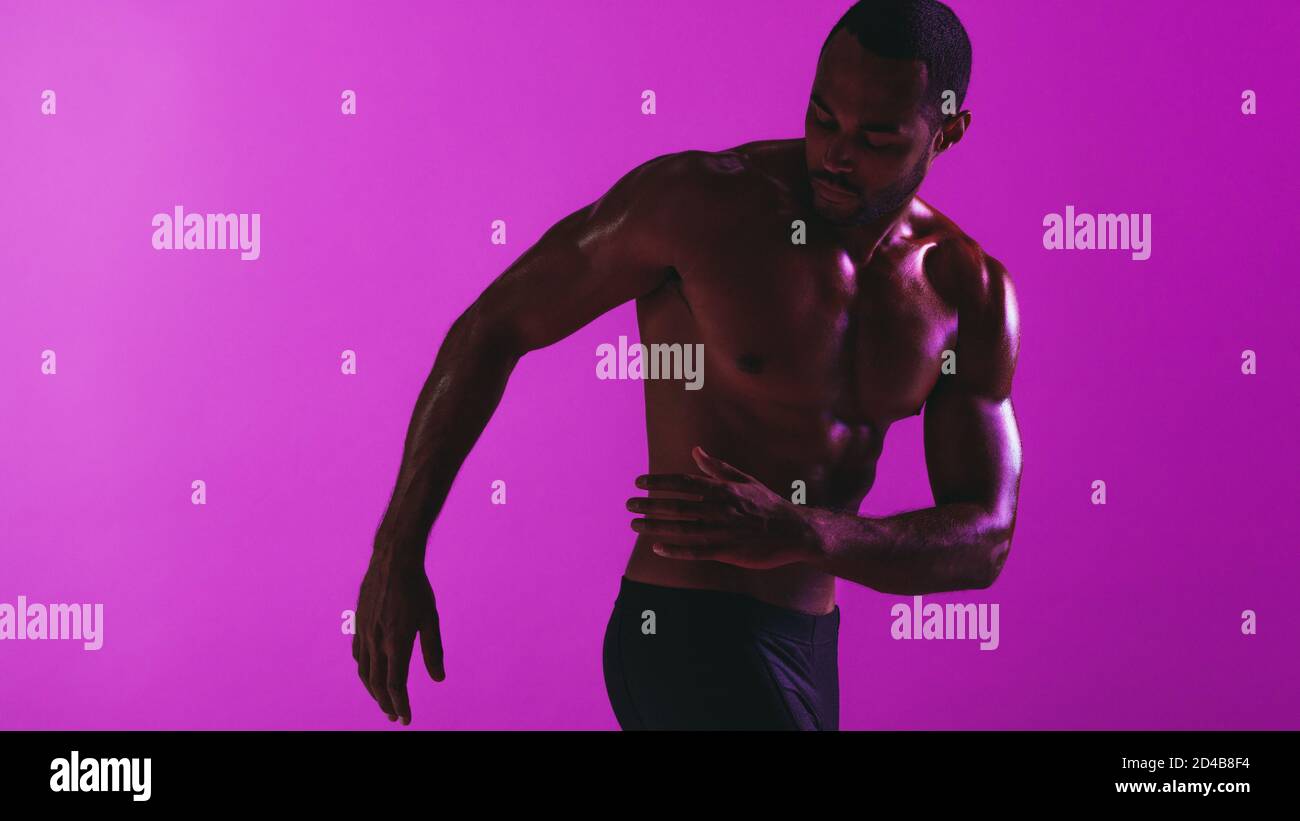 Athletic Mann arbeiten auf lila Hintergrund. Monochromes Fitness-Portrait von fit Athlet beim Workout. Stockfoto