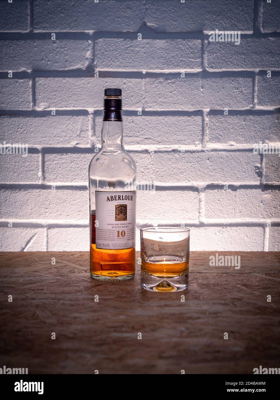 Eine halbe volle Flasche schottischen Whisky aus dem Aberlour Destillerie mit einem Glas vor Backsteinmauer Hintergrund Stockfoto