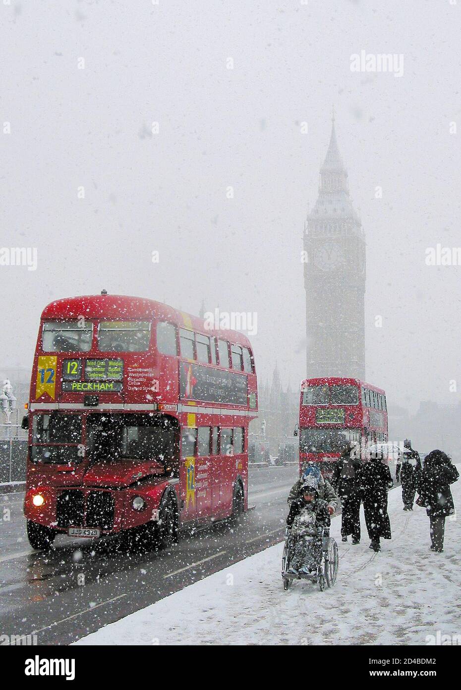 Londoner Busse überqueren die Westminster Bridge im Schnee in London, 8. Januar 2003. Schnee und Frost führten am Mittwoch zu Reiseunterbrechungen in ganz Großbritannien. REUTERS/Jonathan Bainbridge ASA Stockfoto