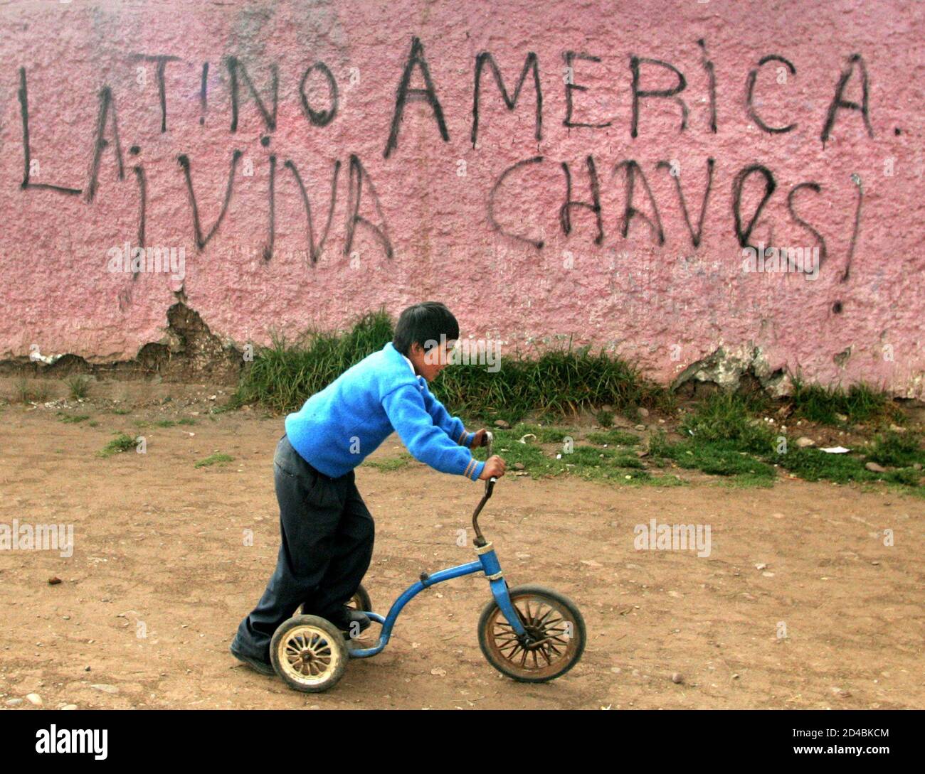 Ein Kind ist in der Nähe von Graffiti gemalt von Unterstützer des venezolanischen Präsidenten Hugo Chavez an einer Wand in Cusco, 6. Dezember 2004, vor einem Gipfel der südamerikanischen Präsidenten in Peru gesehen. Der Gipfel, die am 9. Dezember mit der Unterzeichnung einer Erklärung zum Einrichten einer südamerikanischen Staatengemeinschaft soll die Region Schlagkraft als Handelsblock und politische Kraft zu steigern und ebnet den Weg für eine mögliche gemeinsame Währung eines Tages ihren Höhepunkt finden. Stockfoto