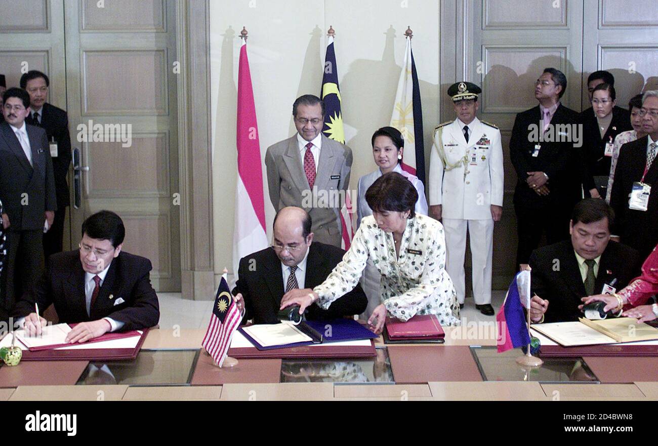 Der malaysische Premierminister Mahathir Mohamad (links stehend) und die philippinische Präsidentin Gloria Macapagal Arroyo sehen die Unterzeichnung eines trilateralen Abkommens durch die Außenminister dreier Länder, Indonesiens Hassan Wirajuda (L), Malaysias Syed Hamid Albar (C) und des philippinischen Innenministers Joey Lina in Putrajaya, nahe Kuala Lumpur, am 7. Mai 2002. Malaysia, Indonesien und die Philippinen unterzeichneten den Pakt zur Bekämpfung des grenzüberschreitenden Terrorismus und zum Bruch eines kämpferischen Netzwerks, das, wie sie sagen, darauf abgestellt ist, einen islamischen Staat aus dem malaiischen Archipel herauszuarbeiten. REUTERS/Zainal Abd Halim ZH/RCS Stockfoto
