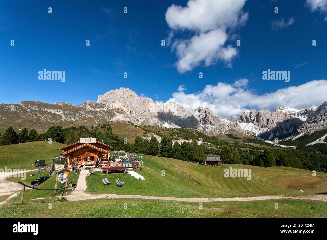 Die Baita Odles Rifugio/ Hütte Ist offen für Geschäfte unter blauem Himmel mit einem atemberaubenden Hintergrund der Geisler Gruppe von Dolomitengipfeln Stockfoto