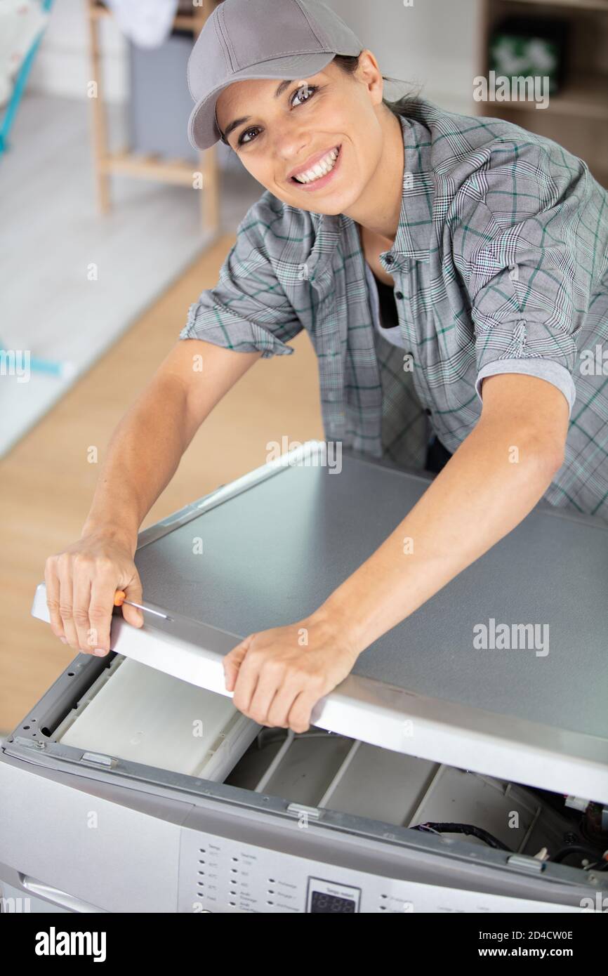 Junge Frau, die Geschirrspüler in der Küche repariert Stockfoto