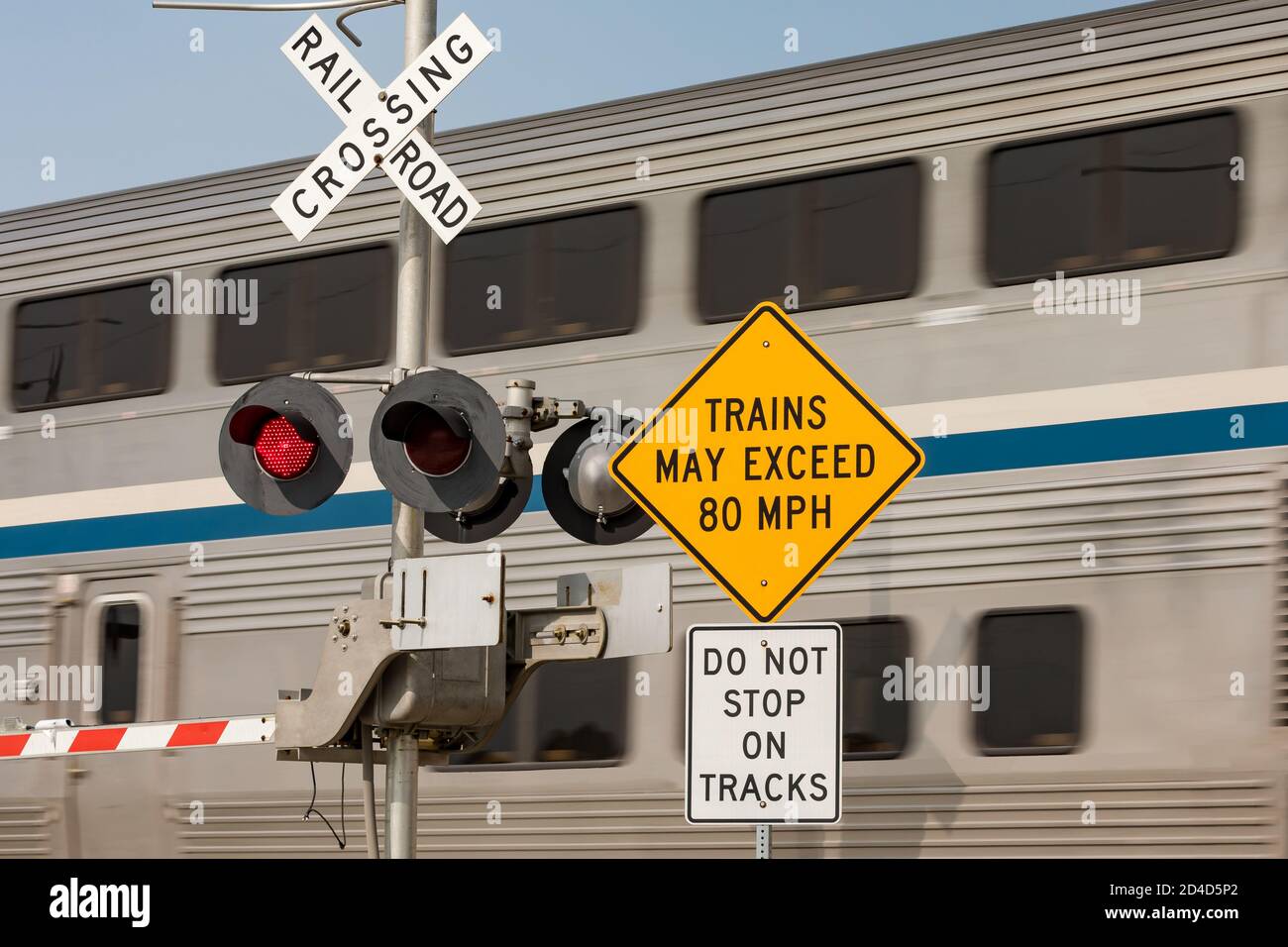 Schnellzug Warnschild am Bahnübergang mit Bewegungsunschärfe des Zuges im Hintergrund. Konzept der Sicherheit, Gefahr und Transport von Bahnübergängen Stockfoto