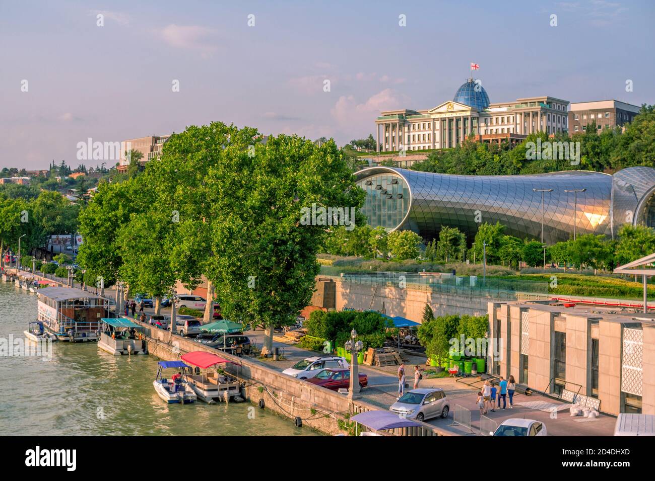 Tiflis/Georgien - 19. Juli 2019: Sommer Stadtbild - Kura Fluss von der Brücke, Präsident Palast und Kulturzentrum Gebäude, grüne Bäume und blauen sk Stockfoto